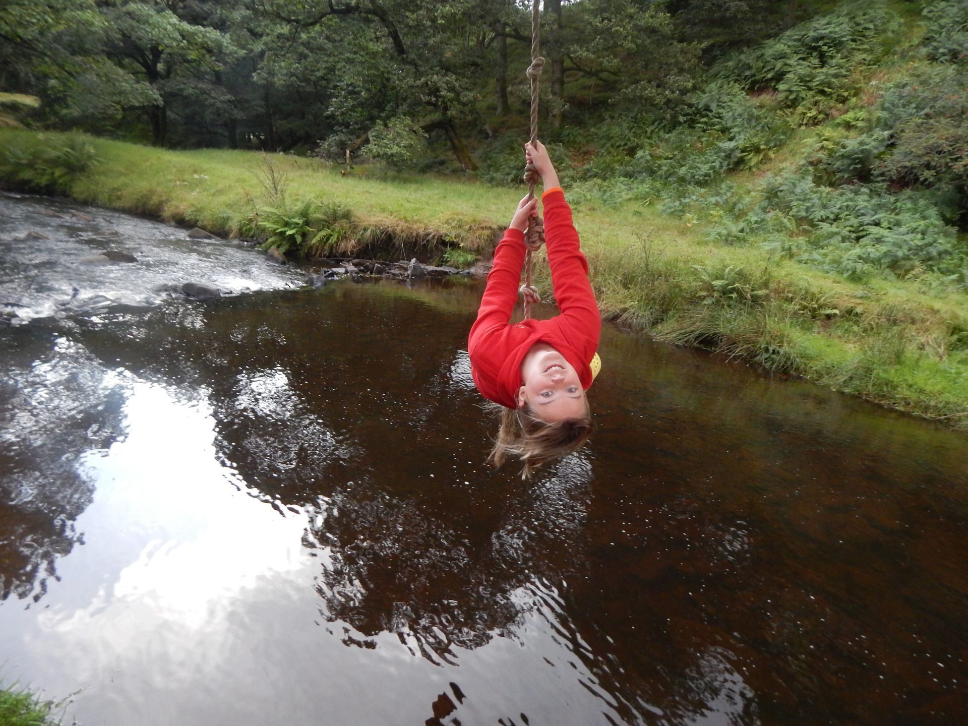 A person is hanging upside down over a river