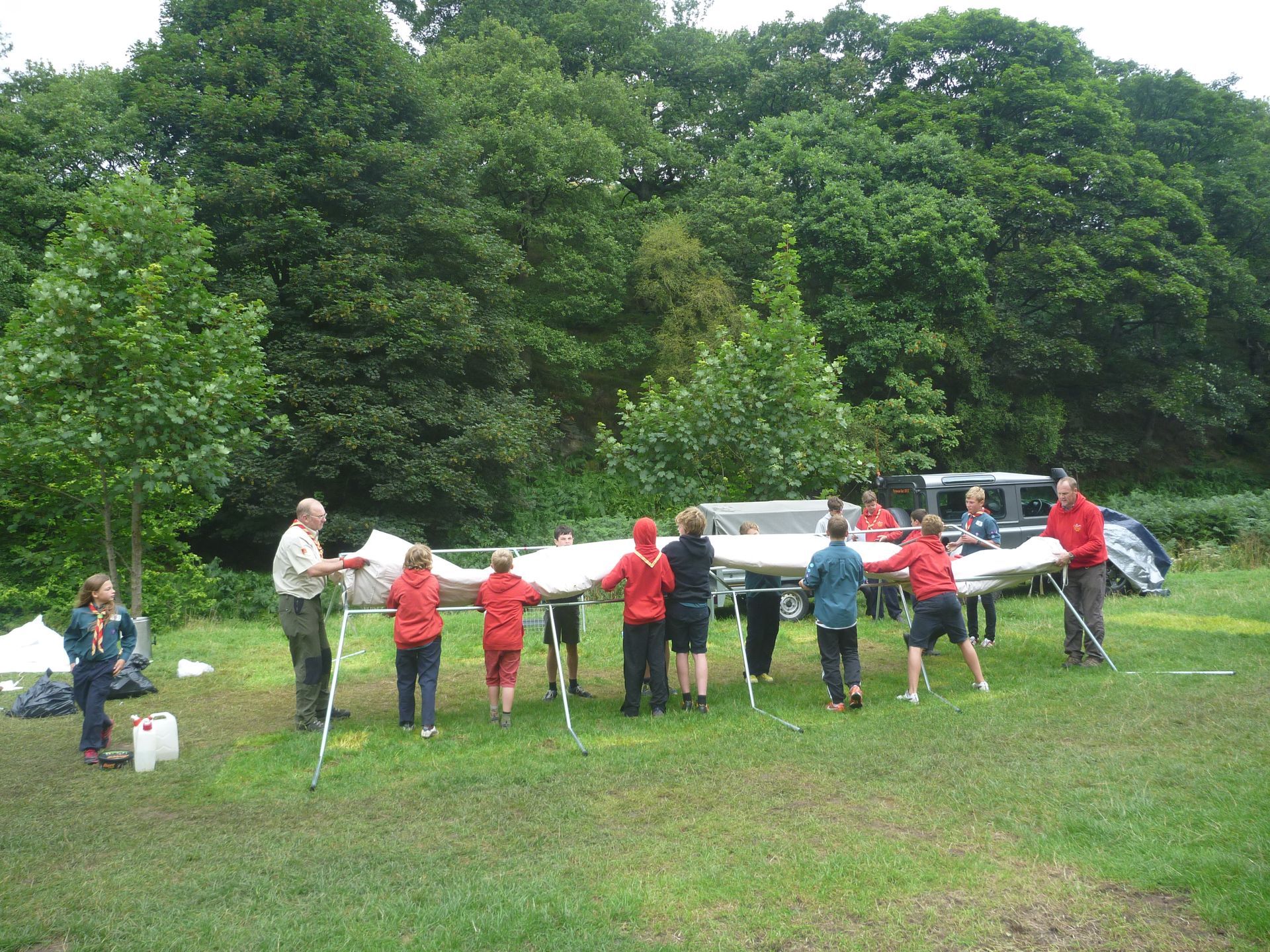A group of people standing in a circle holding a large piece of paper