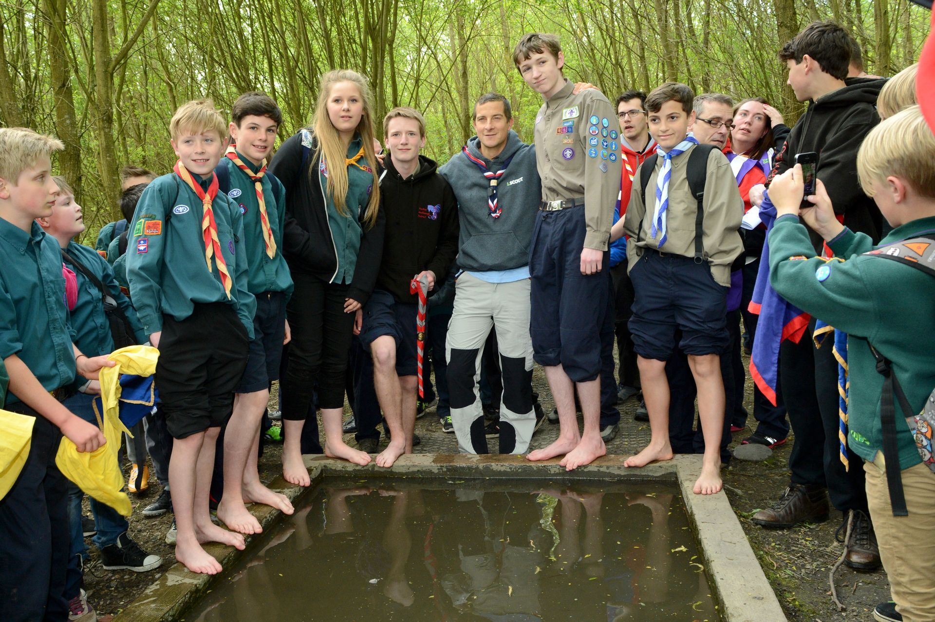 A group of boy scouts standing next to a body of water.