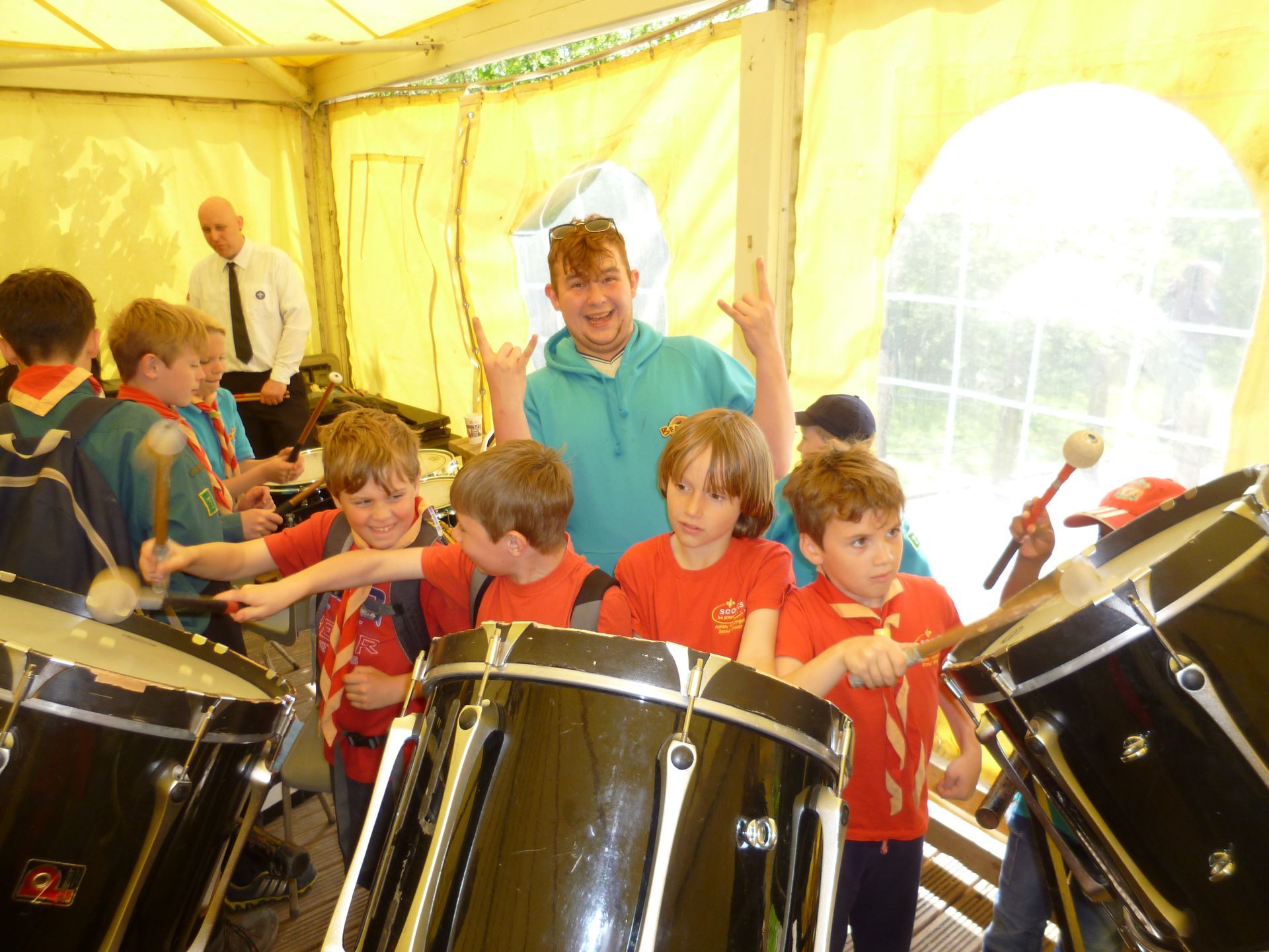 A group of young boys are playing drums in a tent
