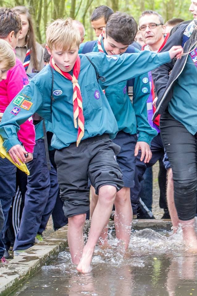 A group of boy scouts are standing in a puddle of water.