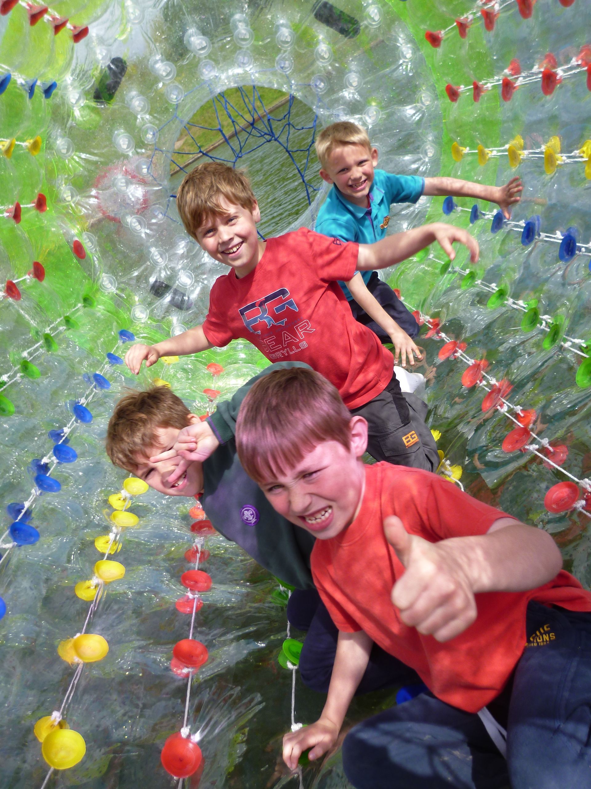 A group of young boys are playing on a water roller coaster and one of them is giving a thumbs up.