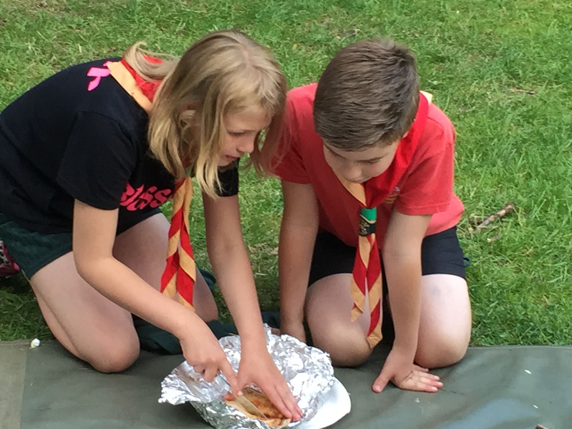 A boy and a girl are looking at a piece of food