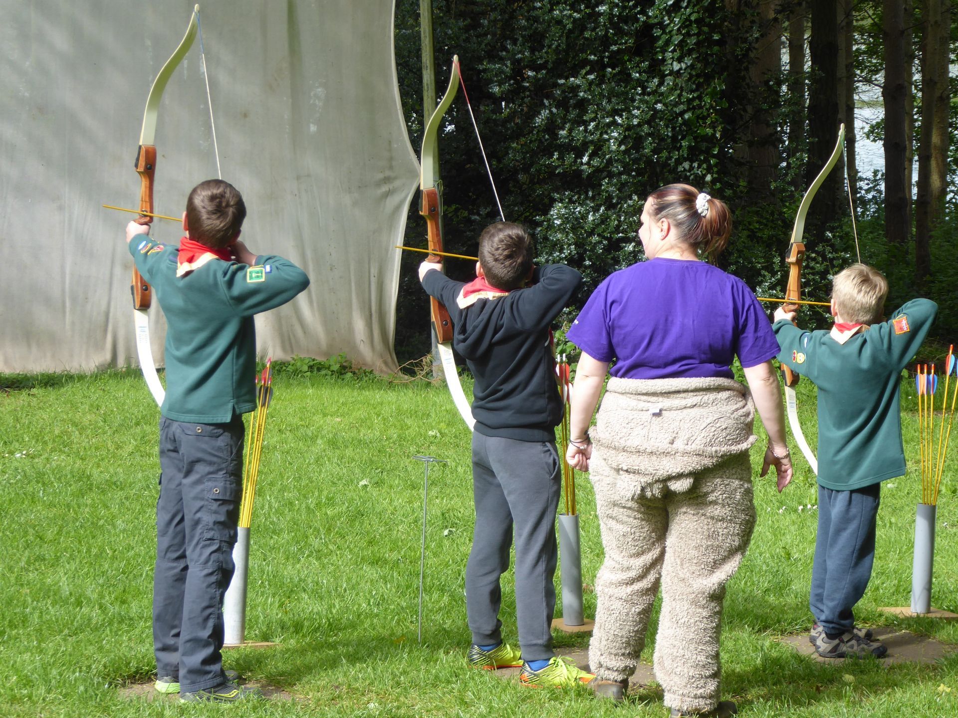 A group of people are practicing archery in a field