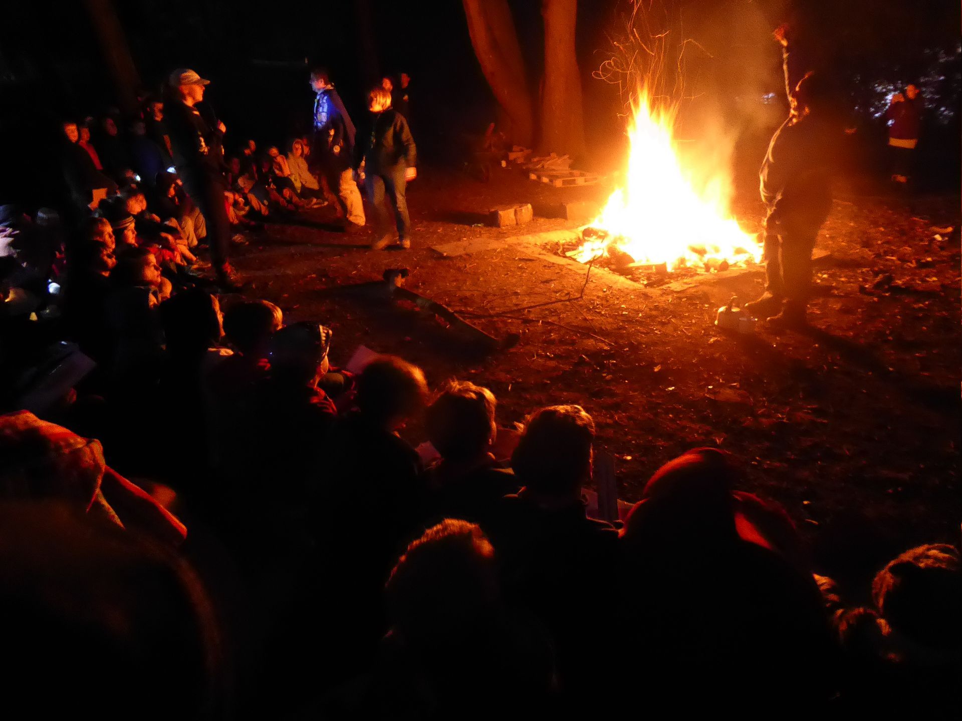 A group of people are gathered around a large fire