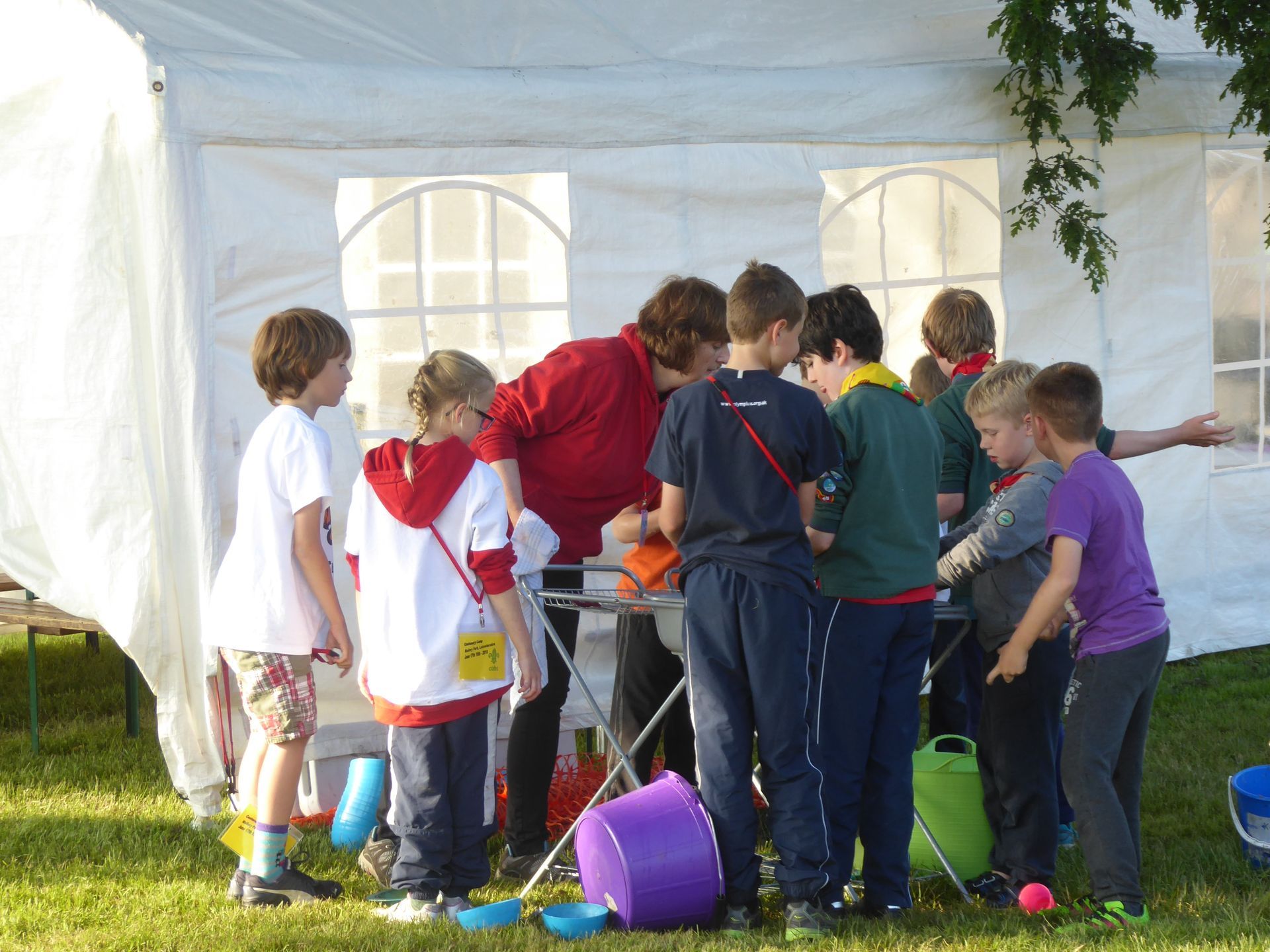 A group of children are gathered around a table under a white tent