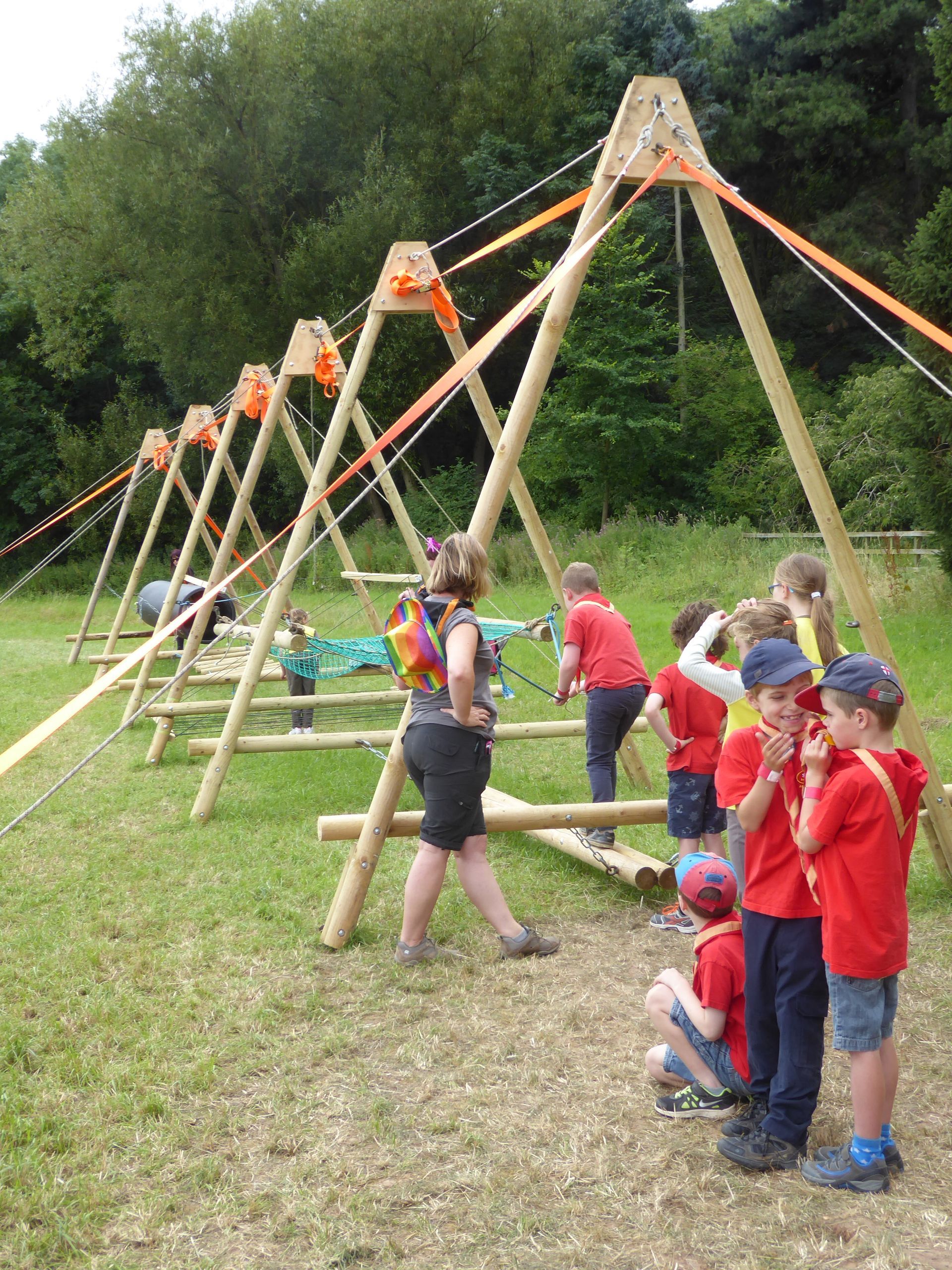 A group of children are standing around a wooden structure in a field.