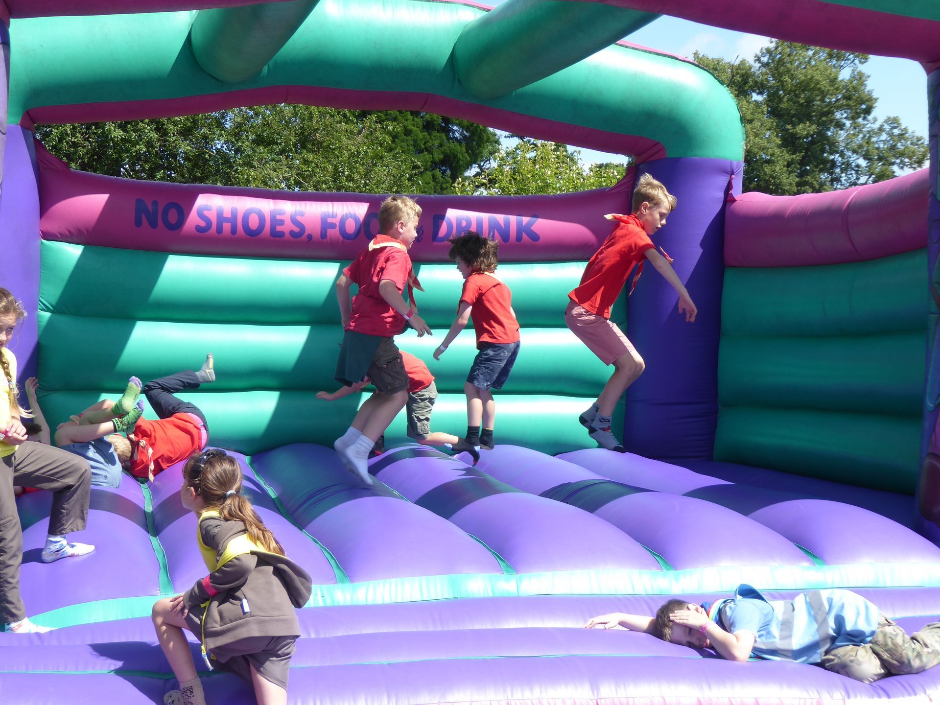 Children are jumping on a bouncy house that says no shoes for kids