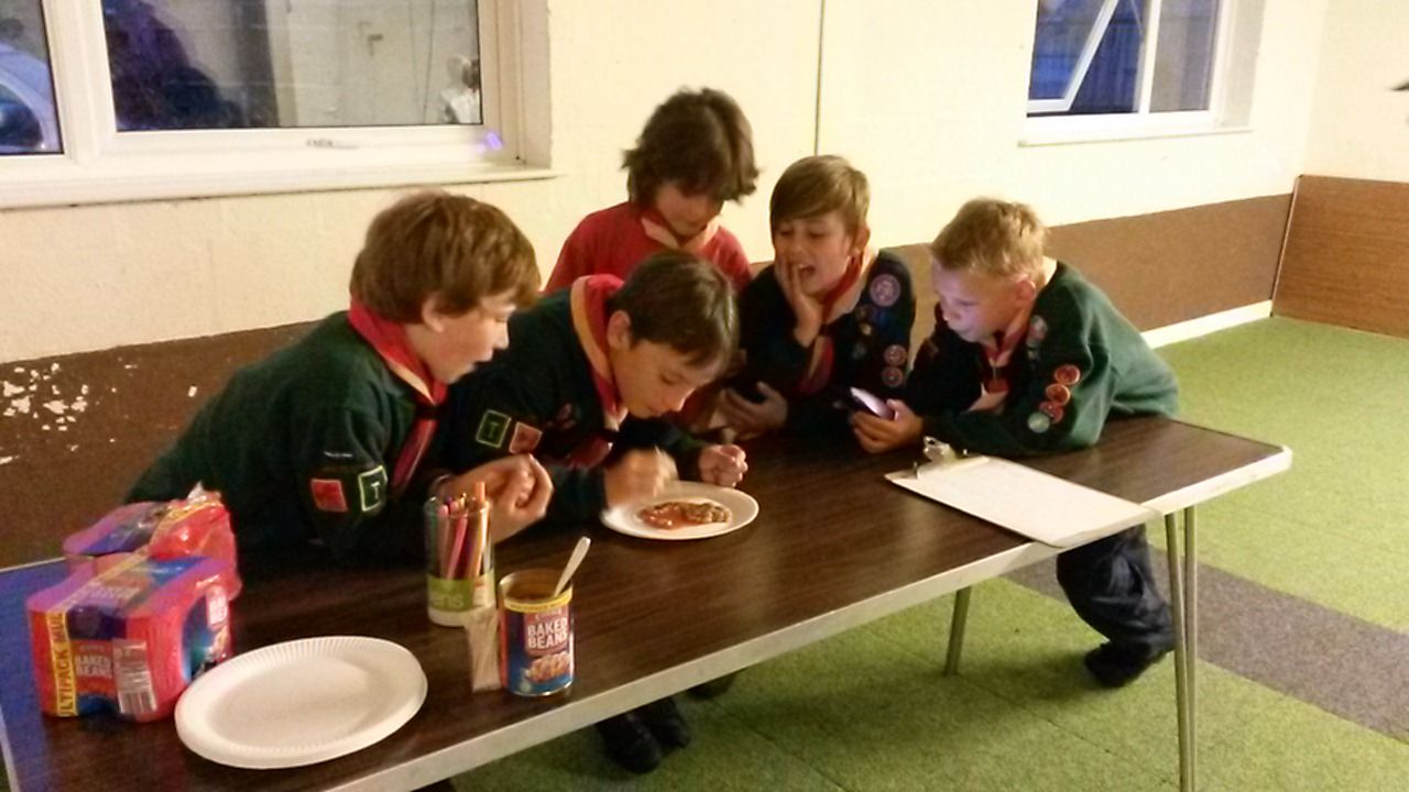 A group of young boys are sitting at a table eating pizza