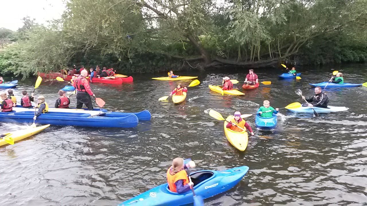 A group of people are paddling kayaks on a river.
