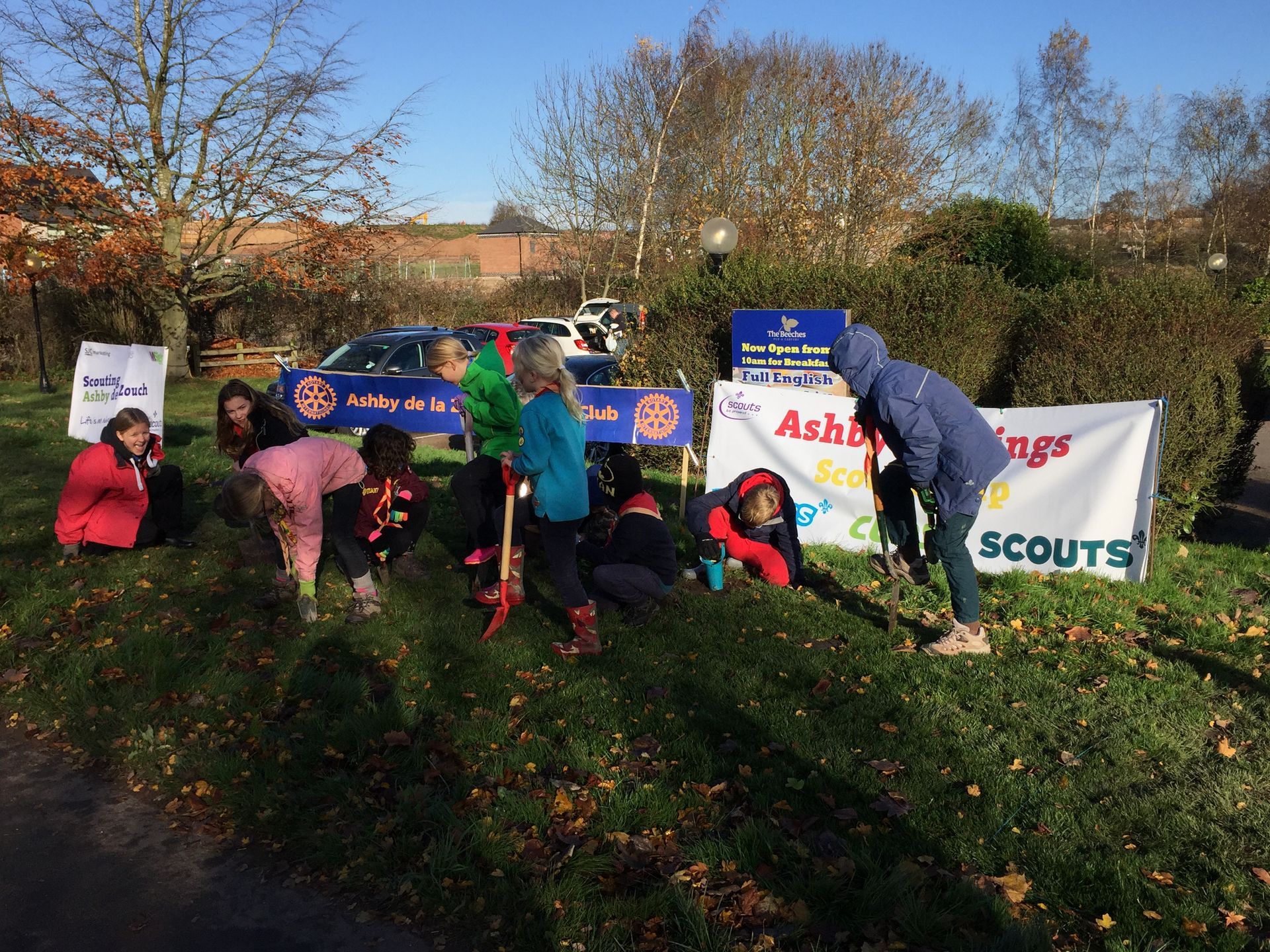 A group of children are playing in the grass in front of a sign that says ashington scouts