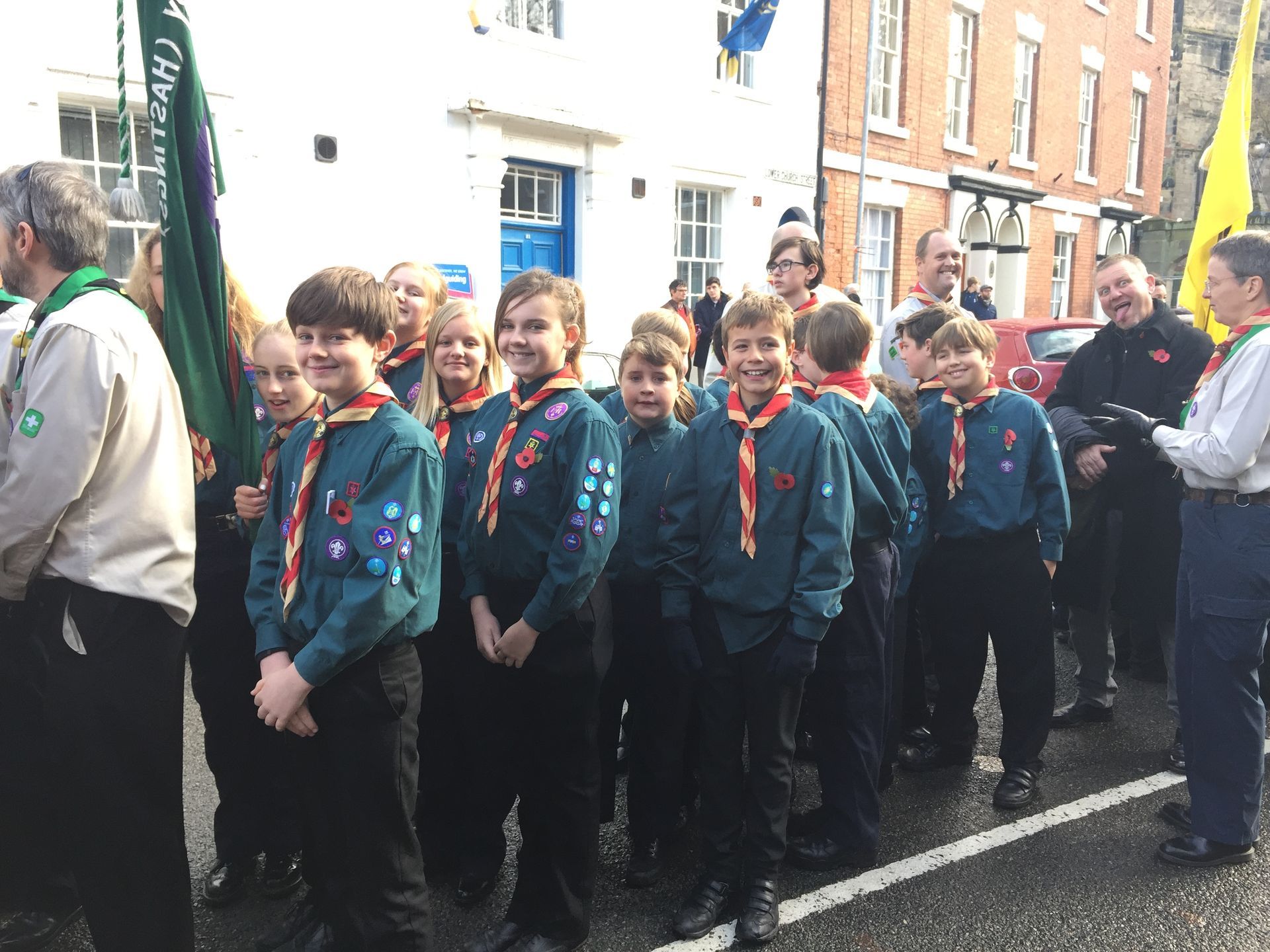 A group of boy scouts are standing in a line in front of a building.