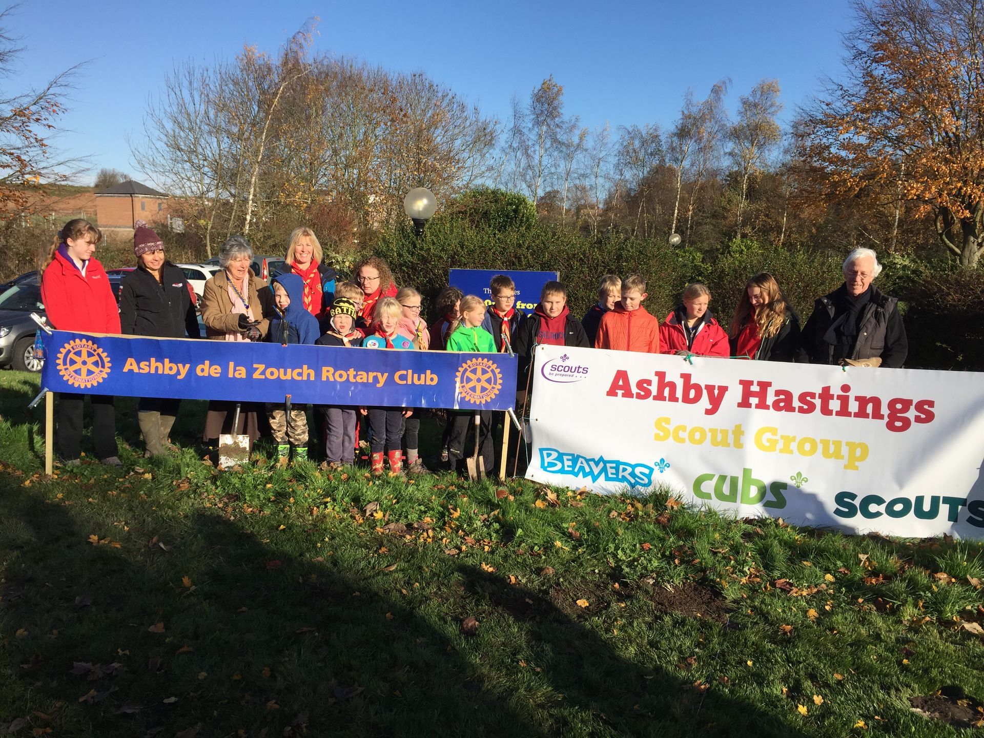 A group of people holding a banner that says ashby hastings scout group cubs scouts