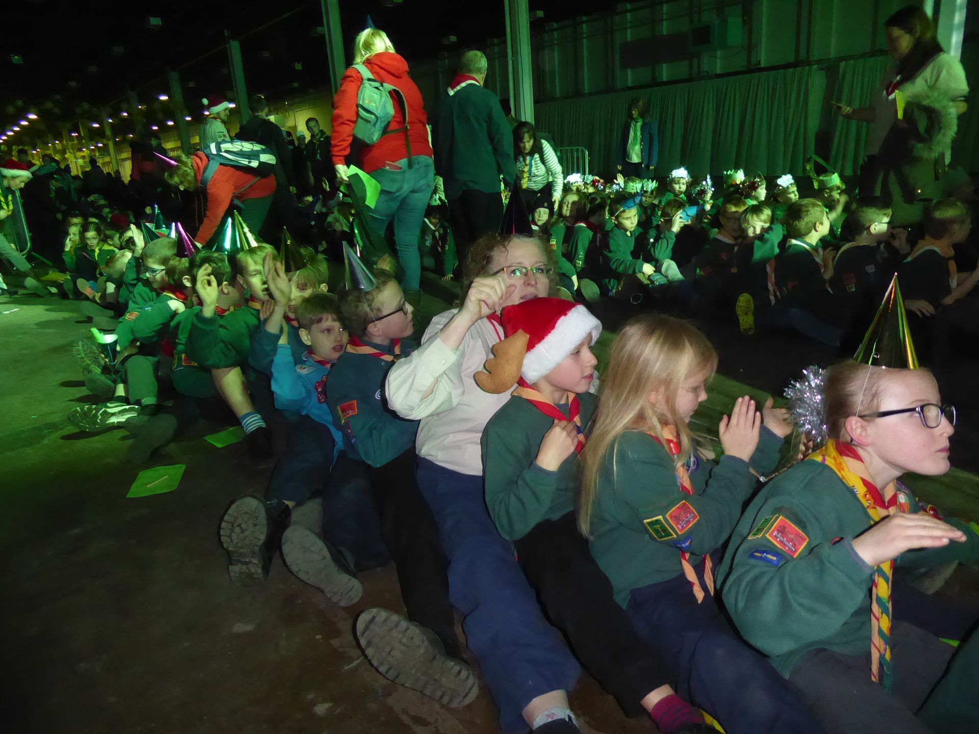 A group of children wearing santa hats are sitting in a row