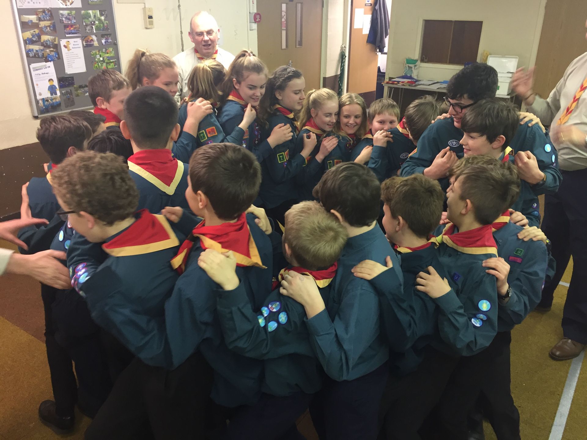 A group of children are hugging each other in a room.