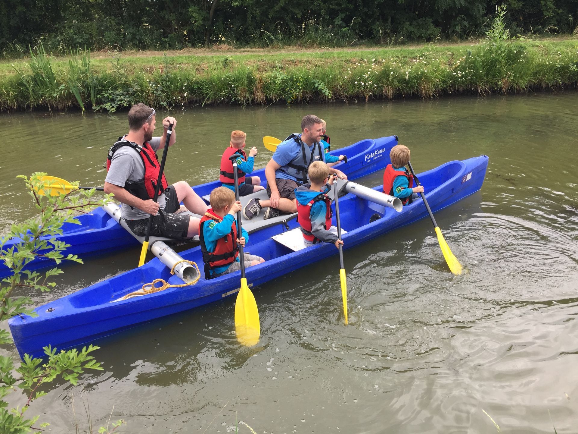 A group of people are in a blue kayak on a river.