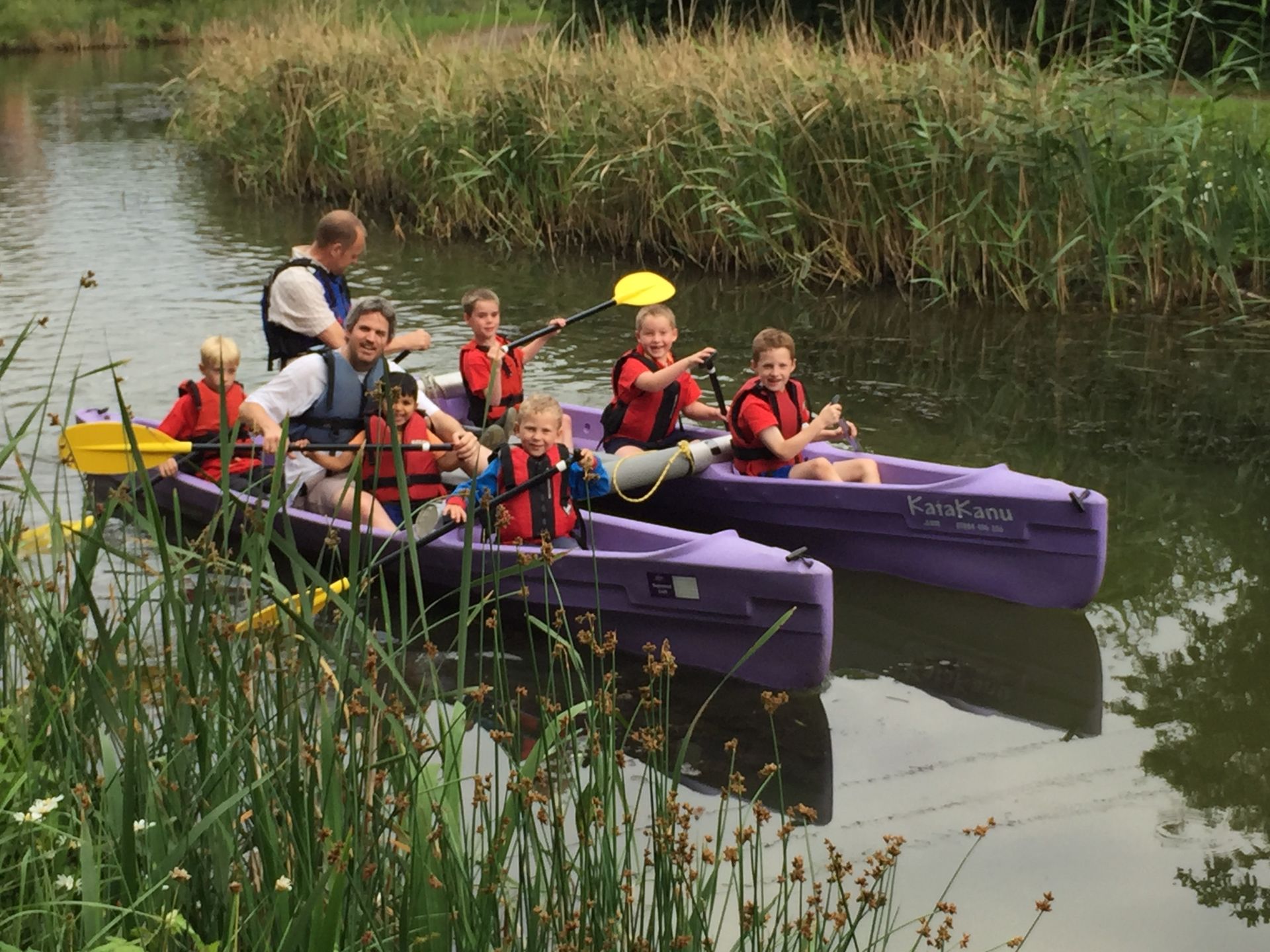 A group of children are in purple kayaks on a river.