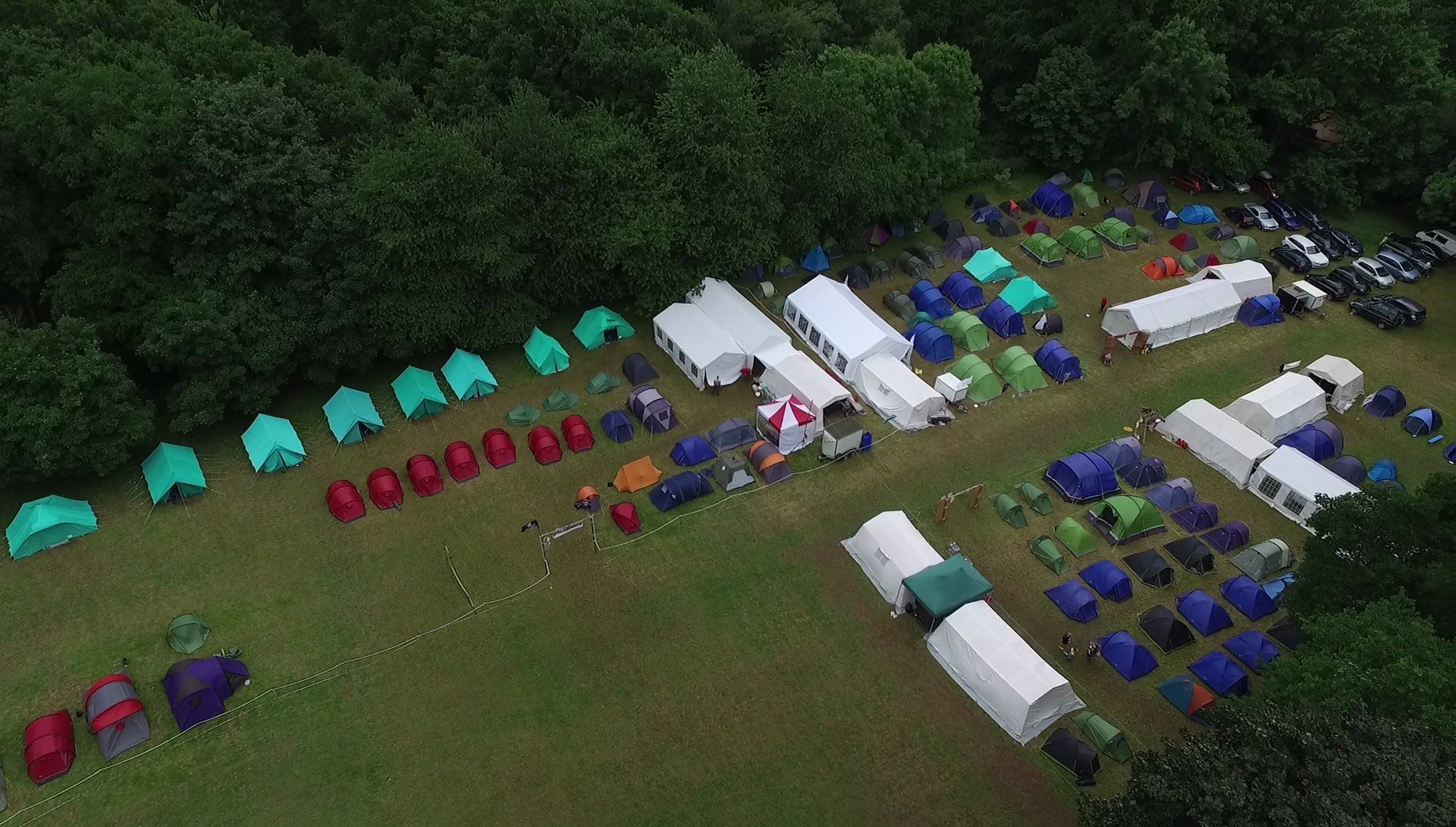 An aerial view of a campground filled with tents and cars.