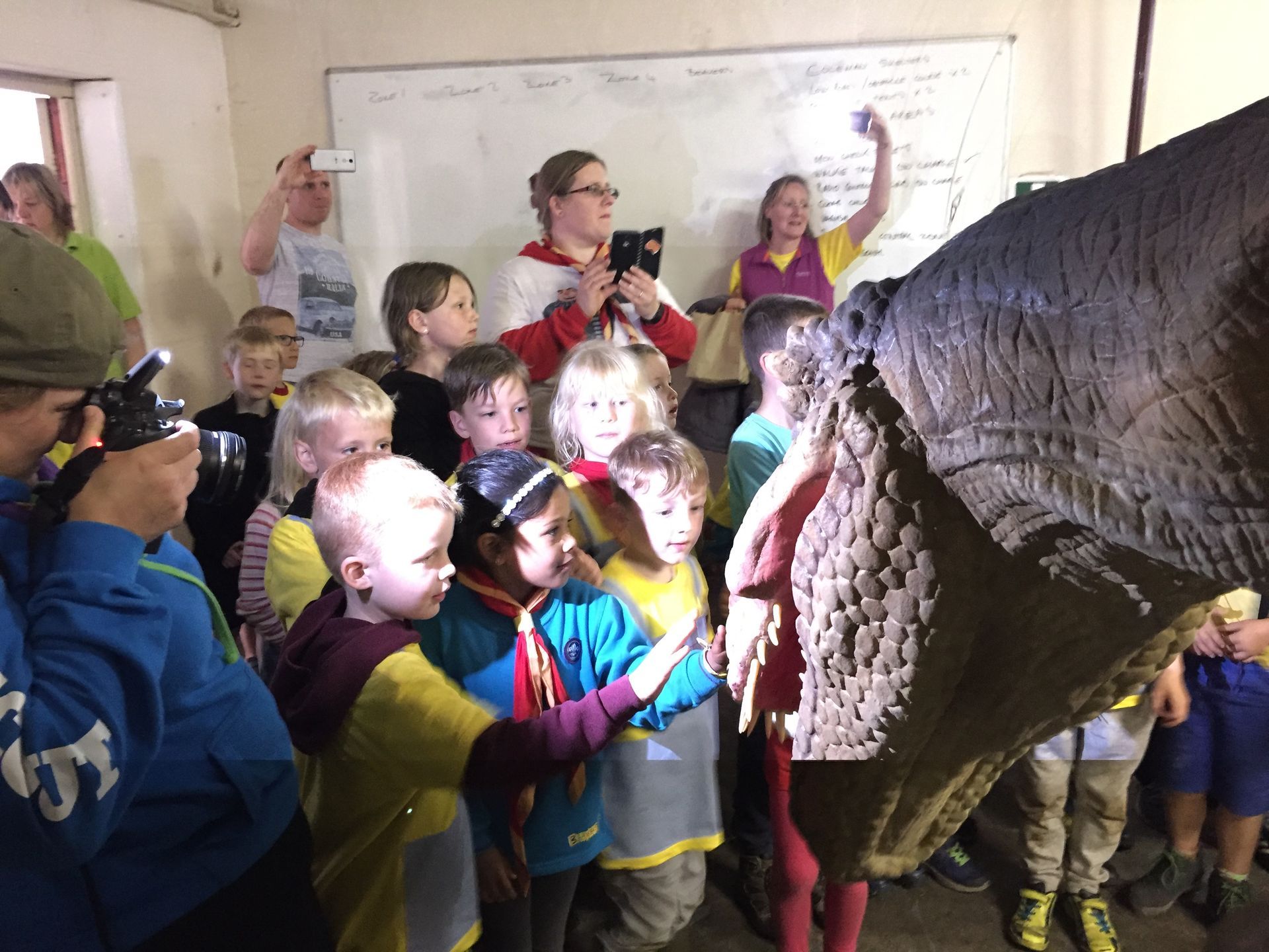 A group of children are standing around a statue of an elephant