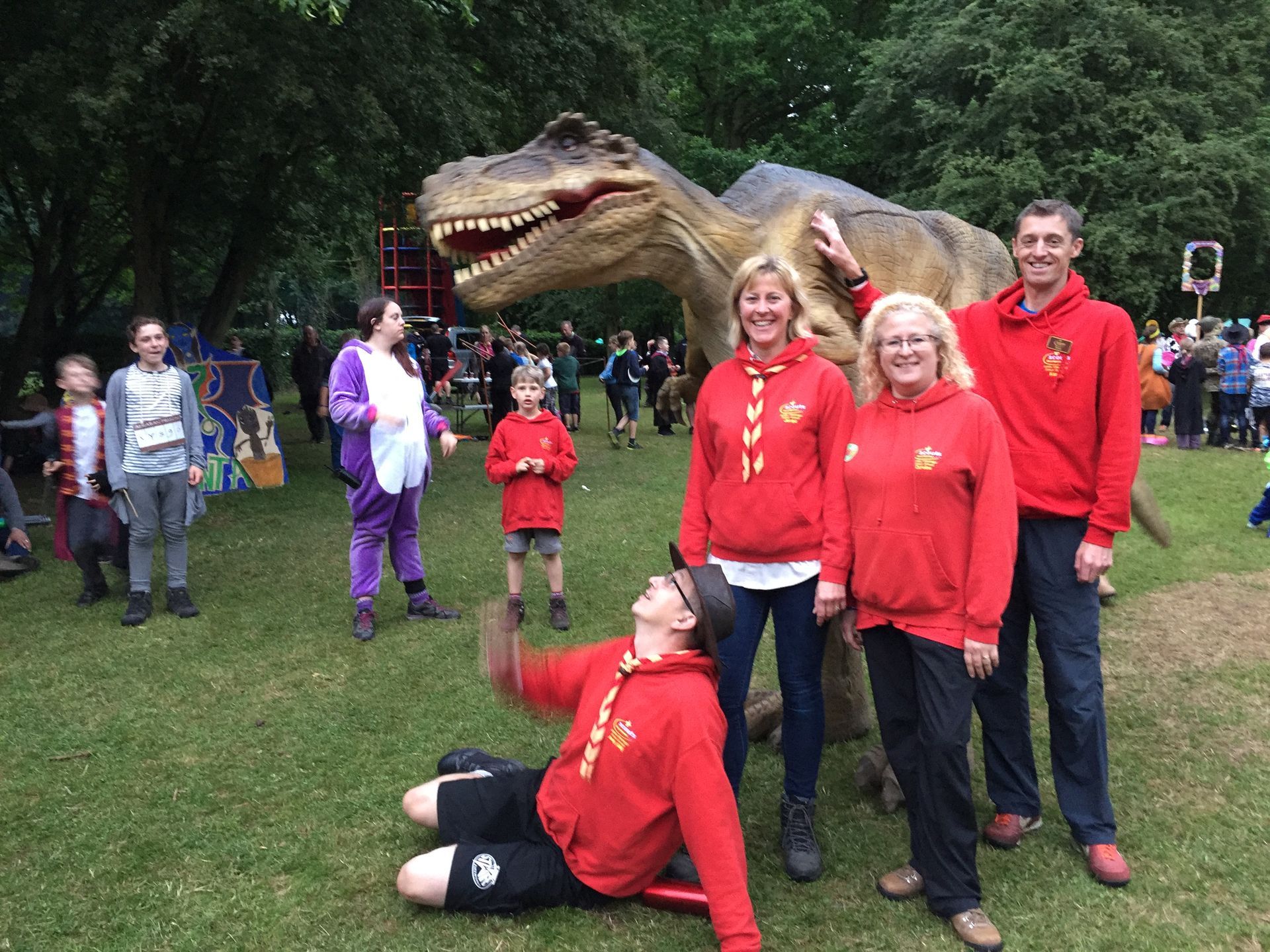 A group of people standing in front of a dinosaur statue.