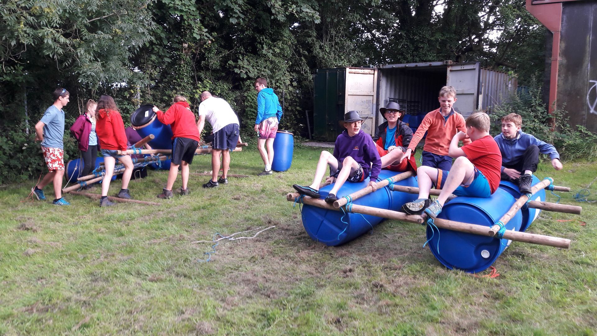 A group of people are sitting on a raft made out of barrels.