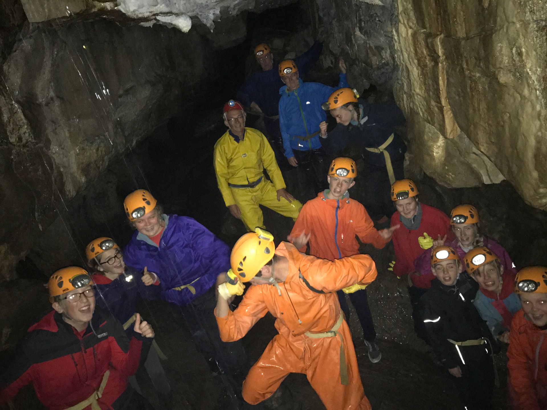 A group of people are standing in a cave wearing helmets