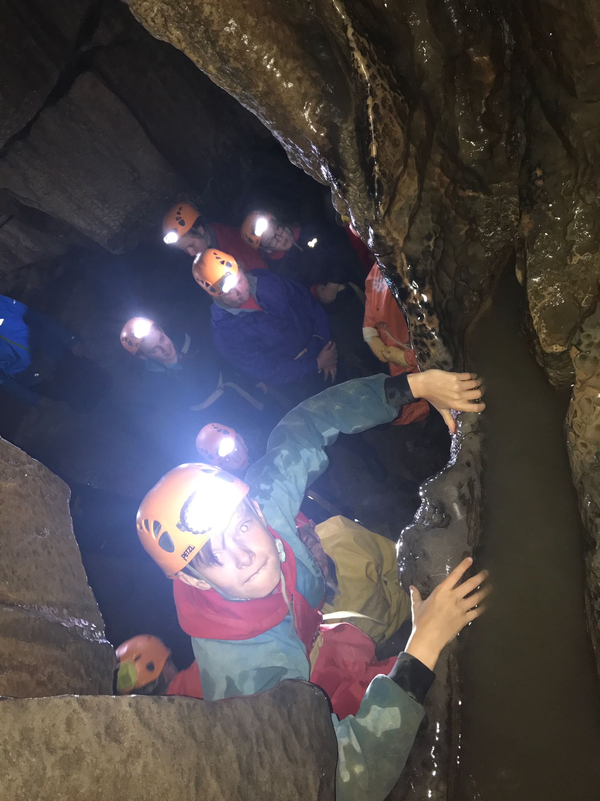 A group of people are climbing up a rock in a cave.