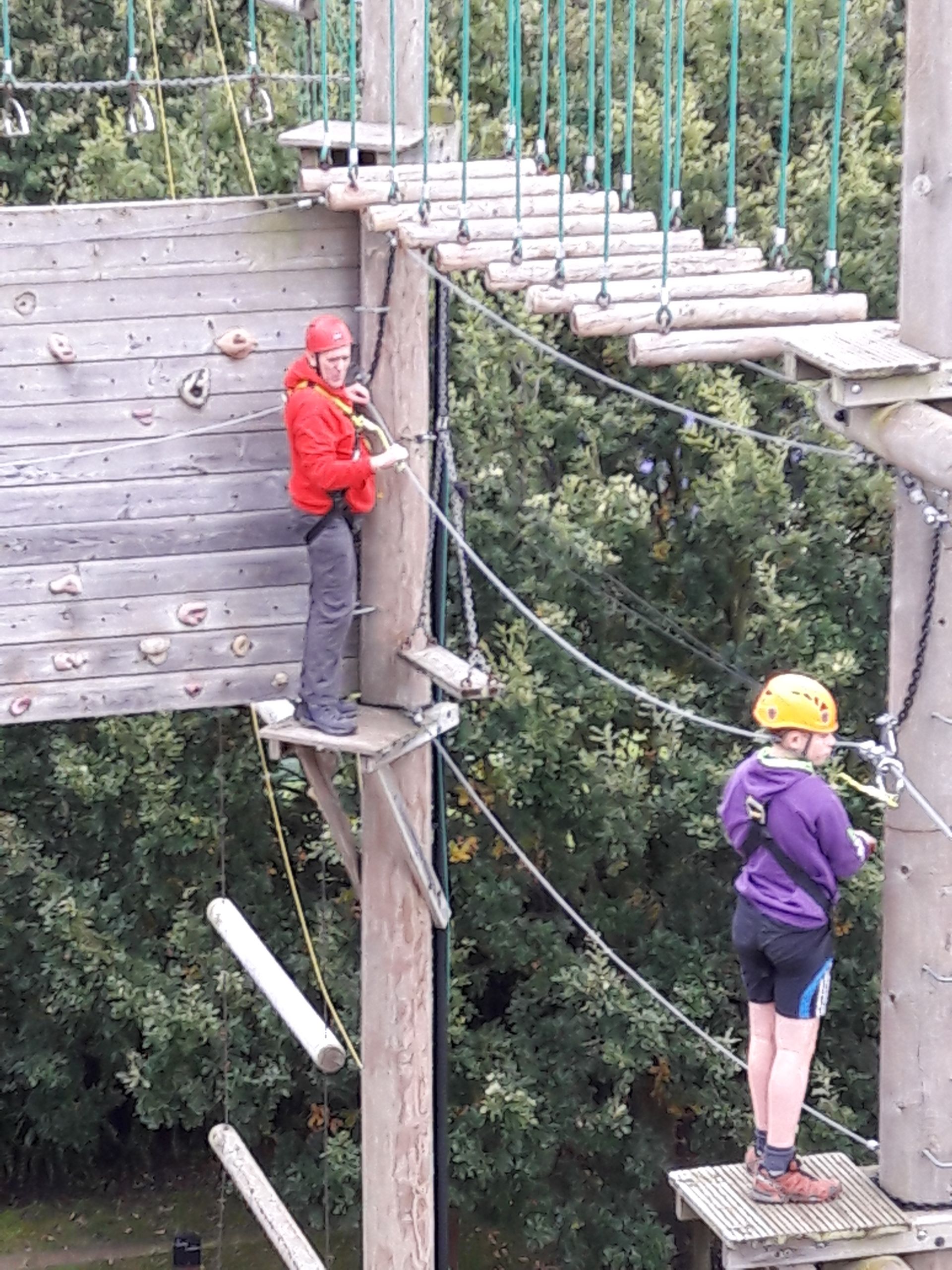 A man and a woman are standing on a ropes course.