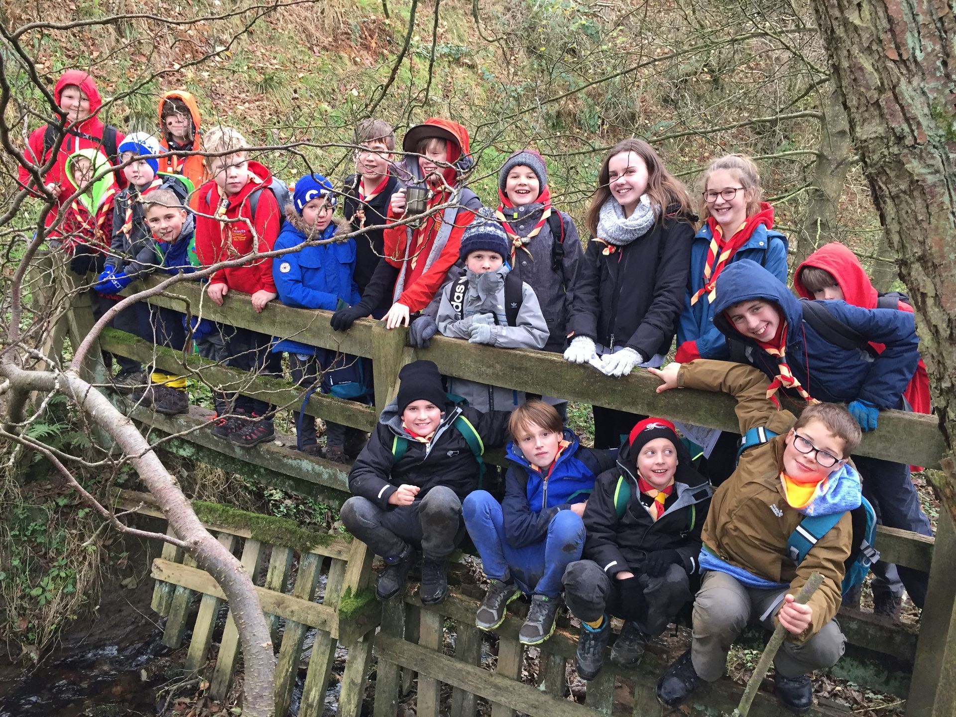 A group of children are sitting on a wooden bridge.