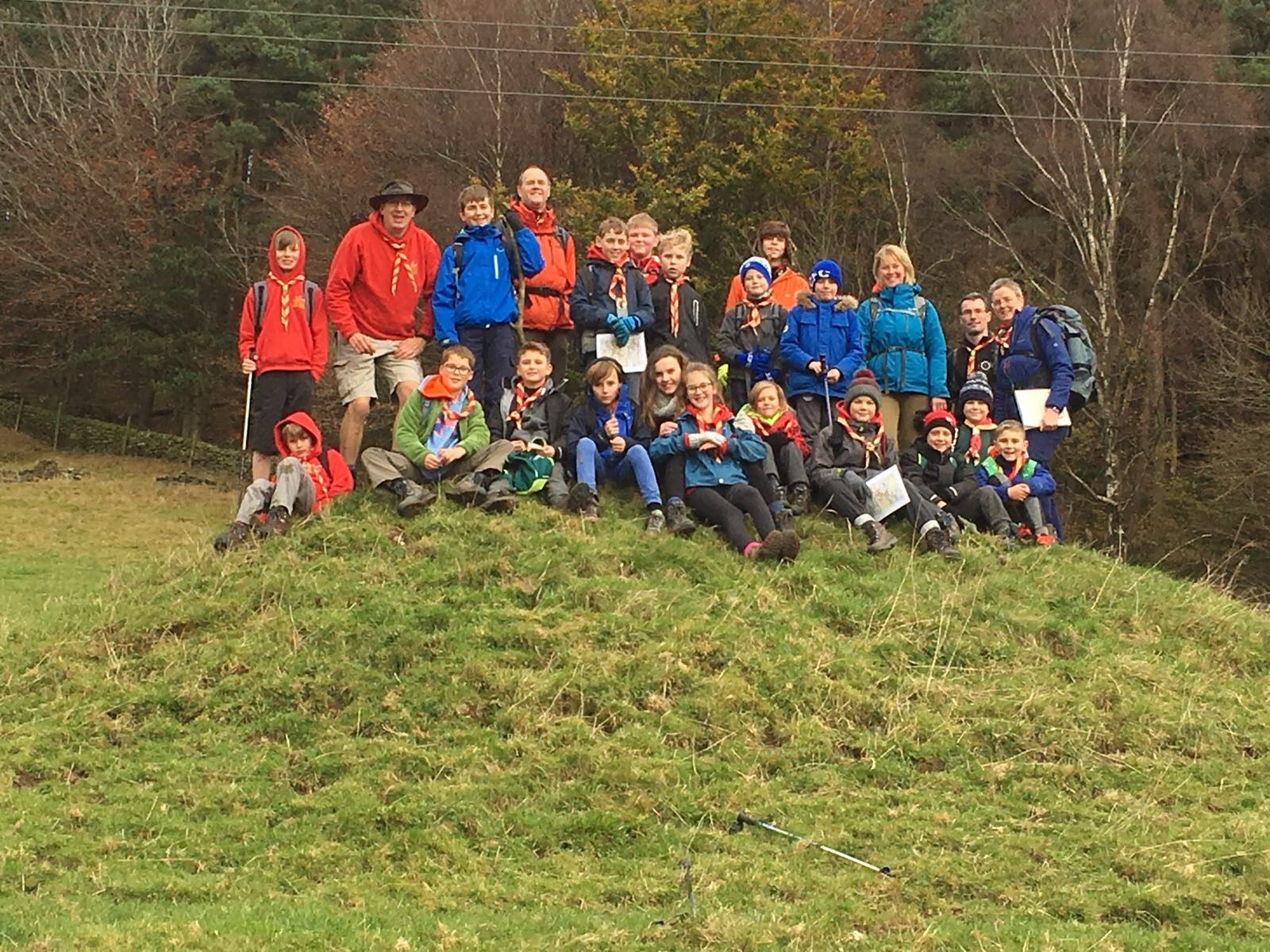 A group of children are sitting on top of a grassy hill.