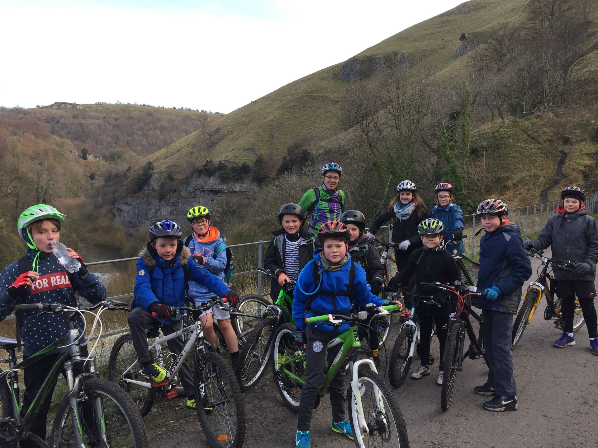 A group of young people are riding bicycles down a road.