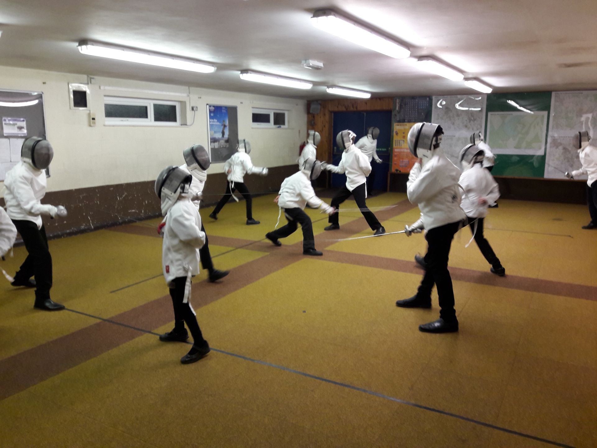 A group of people are practicing fencing in a gym.