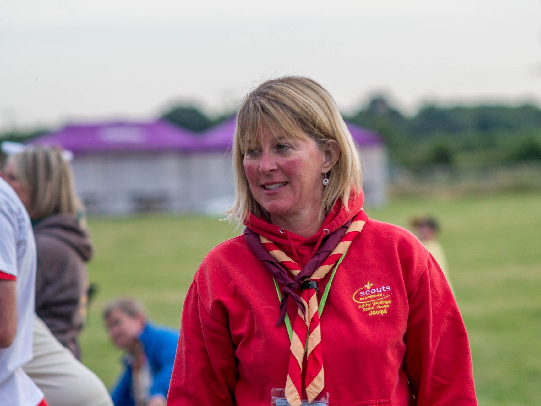 A woman in a red sweatshirt is standing in a field.