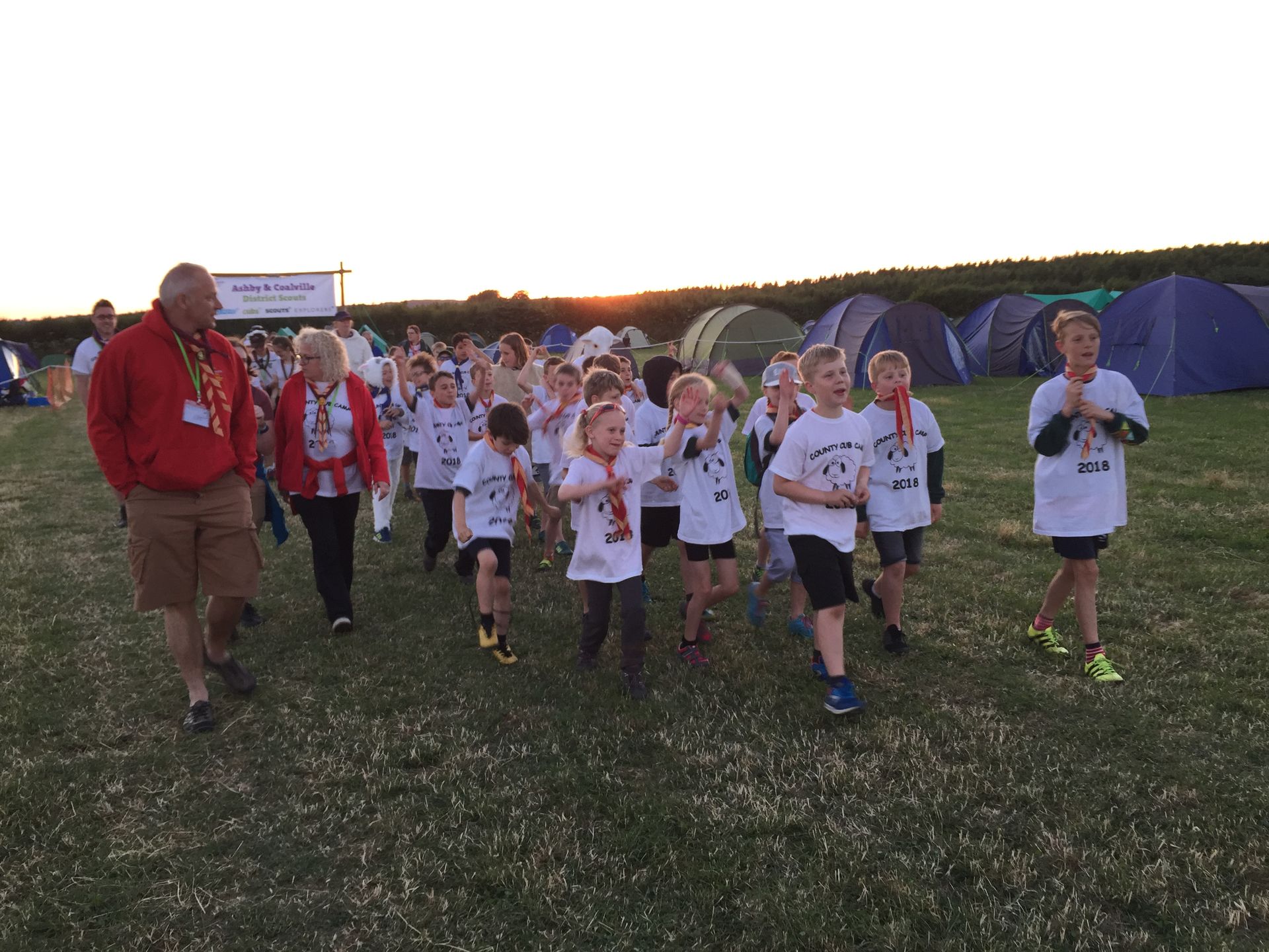 A group of children are running in a field while a man watches