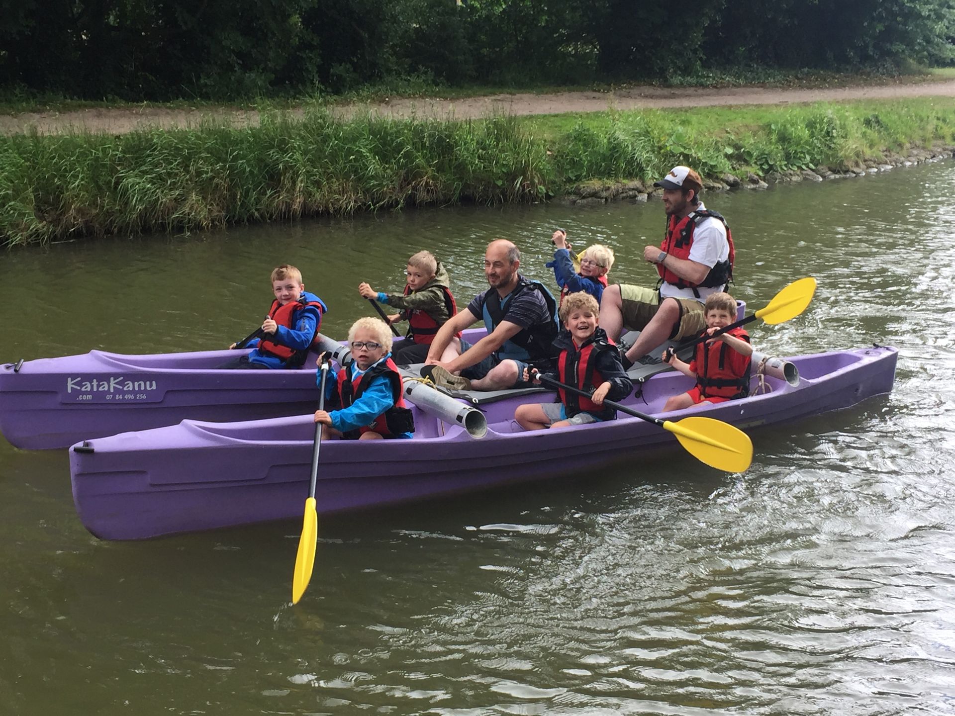 A group of people are in purple kayaks on a river.