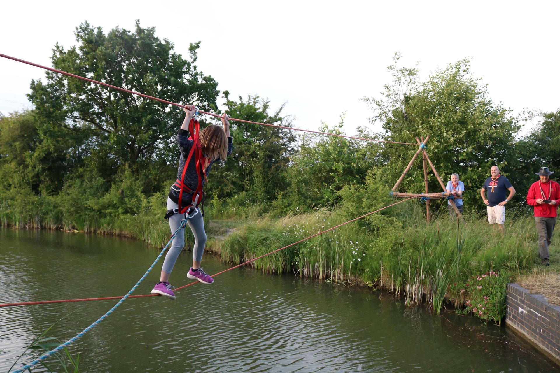 A girl is walking on a rope over a body of water.