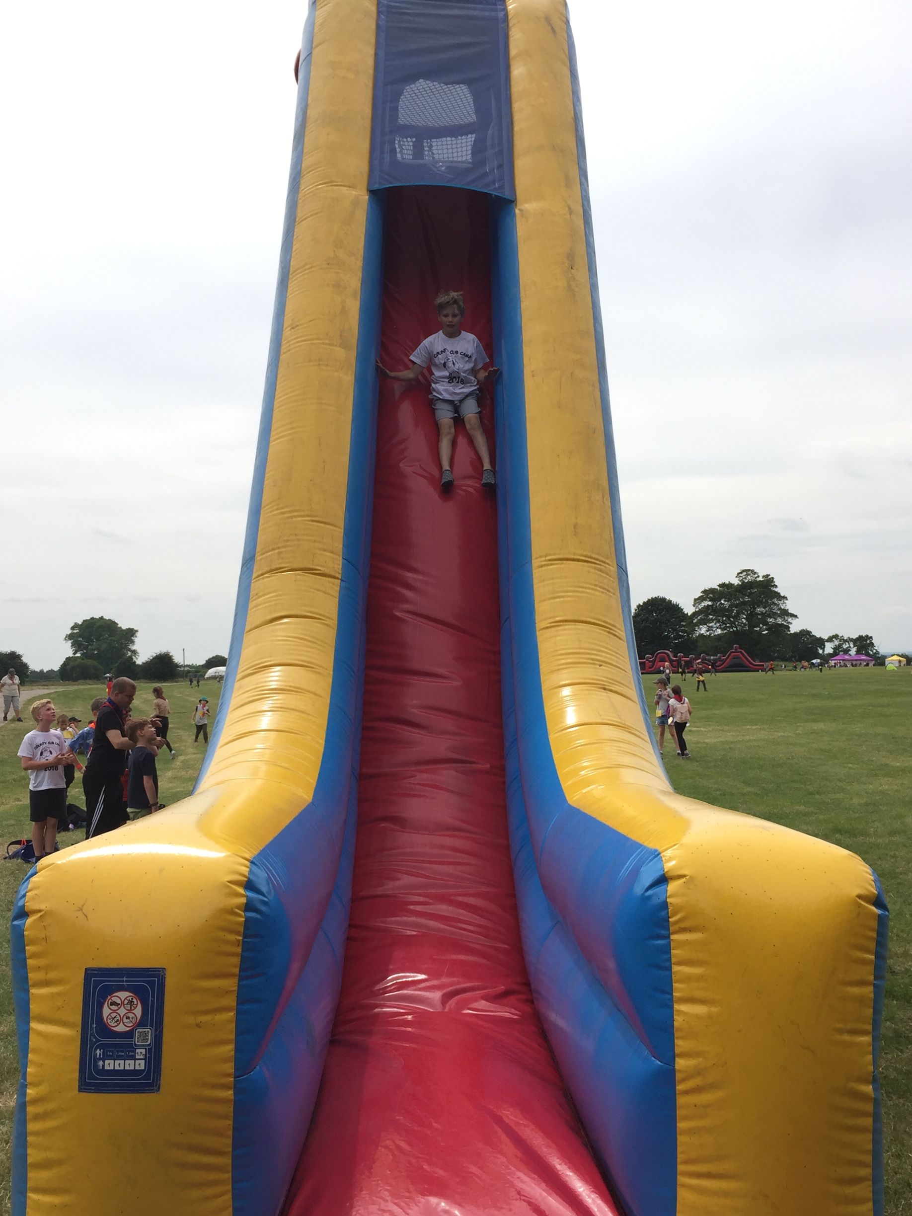 A boy is riding down an inflatable slide in a field.