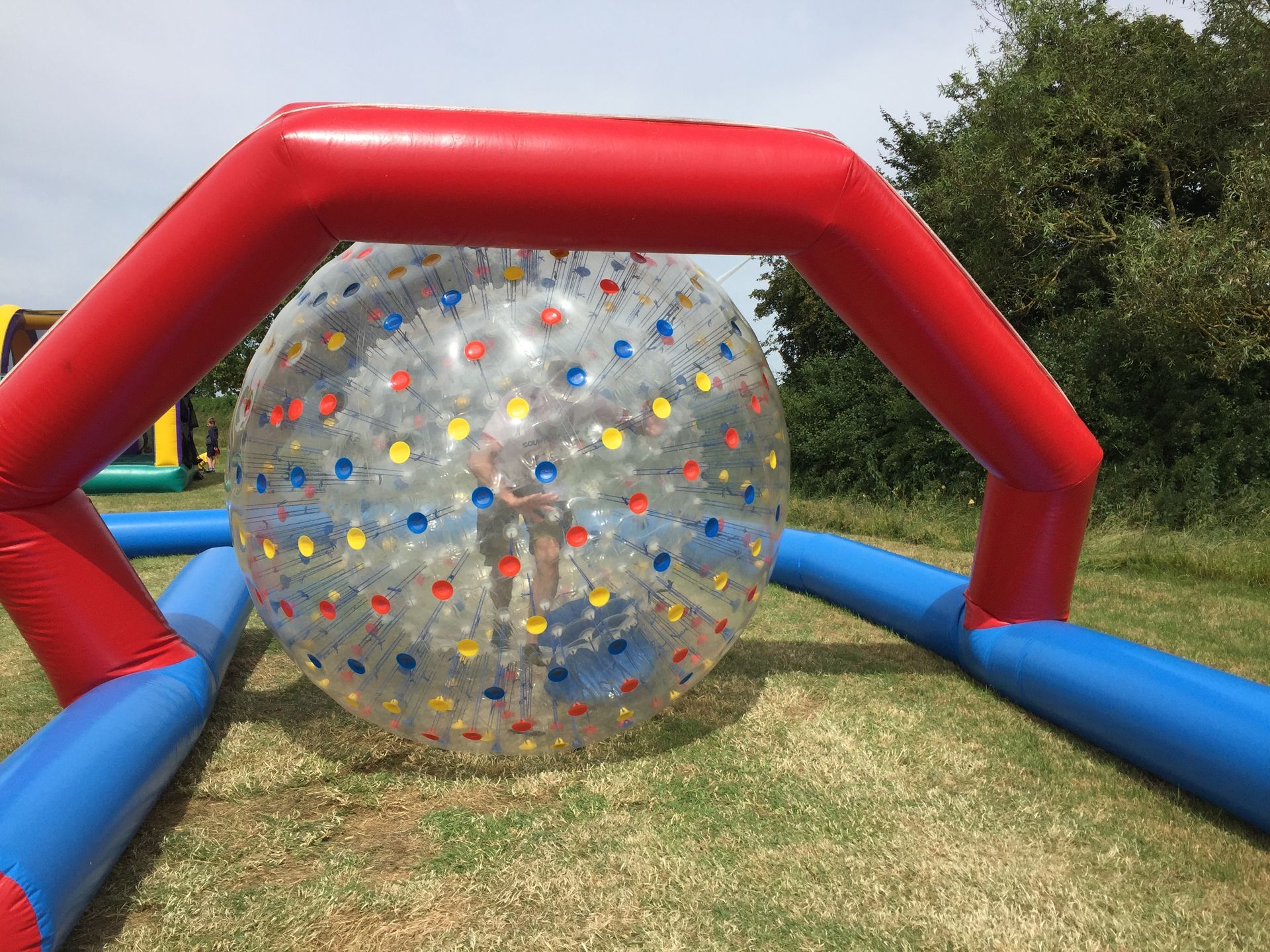 A large inflatable ball with polka dots on it is sitting on top of a lush green field.