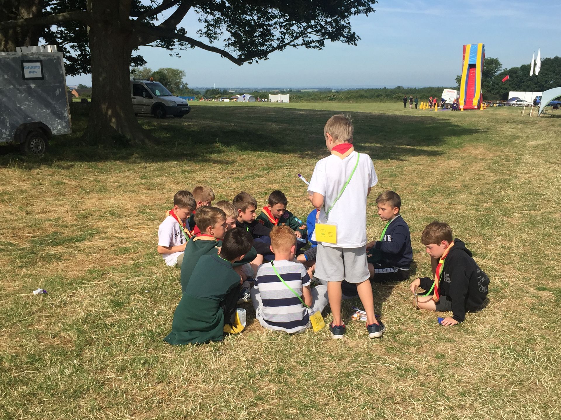 A group of children are sitting in a circle in the grass.
