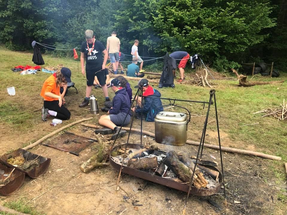 A group of people are sitting around a fire in a field.