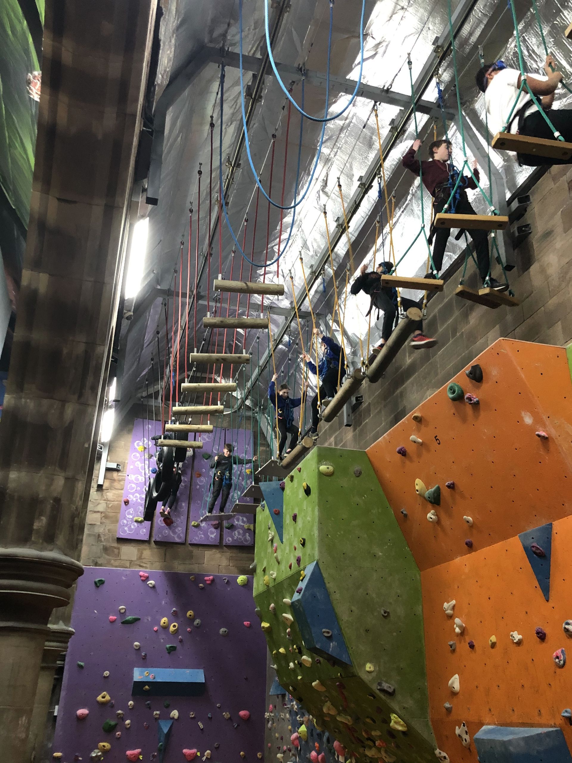 A group of people are climbing a climbing wall.