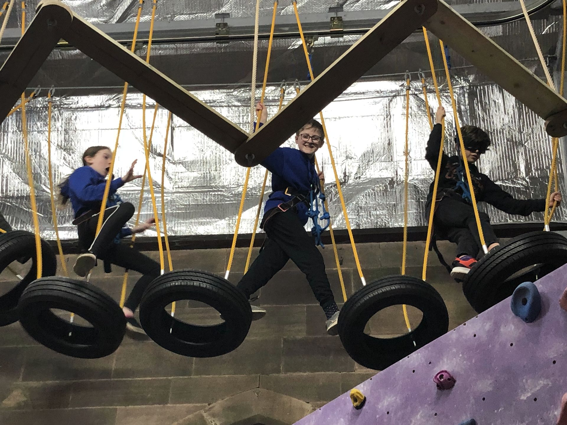A group of children are playing with tires on a climbing wall.
