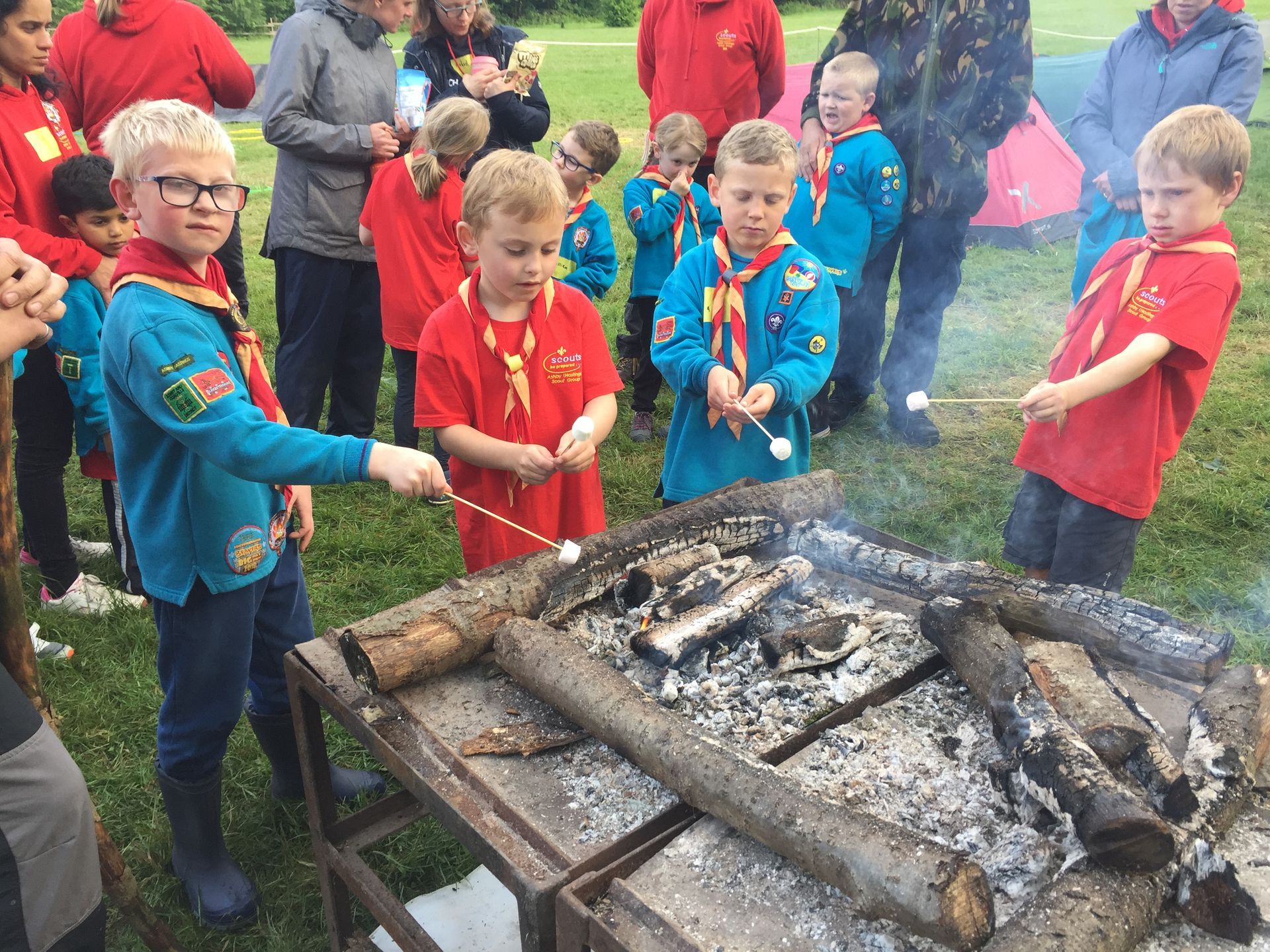 A group of boy scouts are roasting marshmallows over a campfire.
