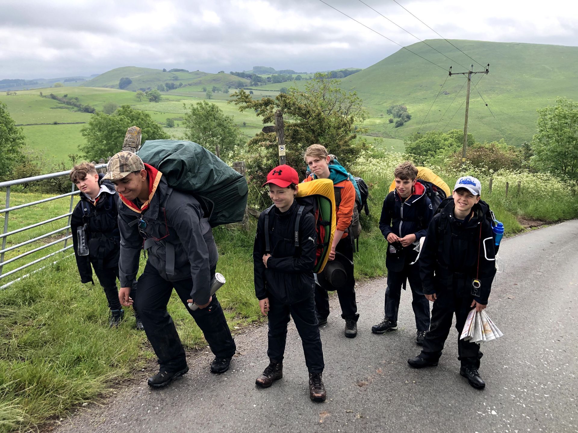 A group of people with backpacks are walking down a road.