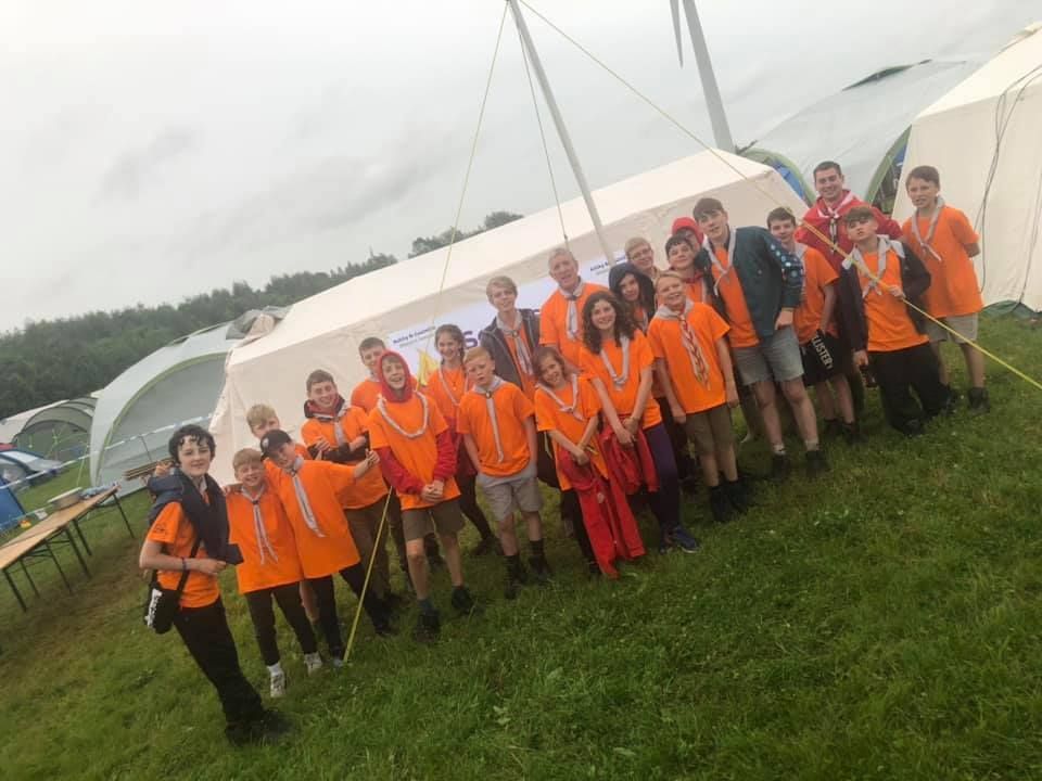 A group of young people are posing for a picture in front of a tent.