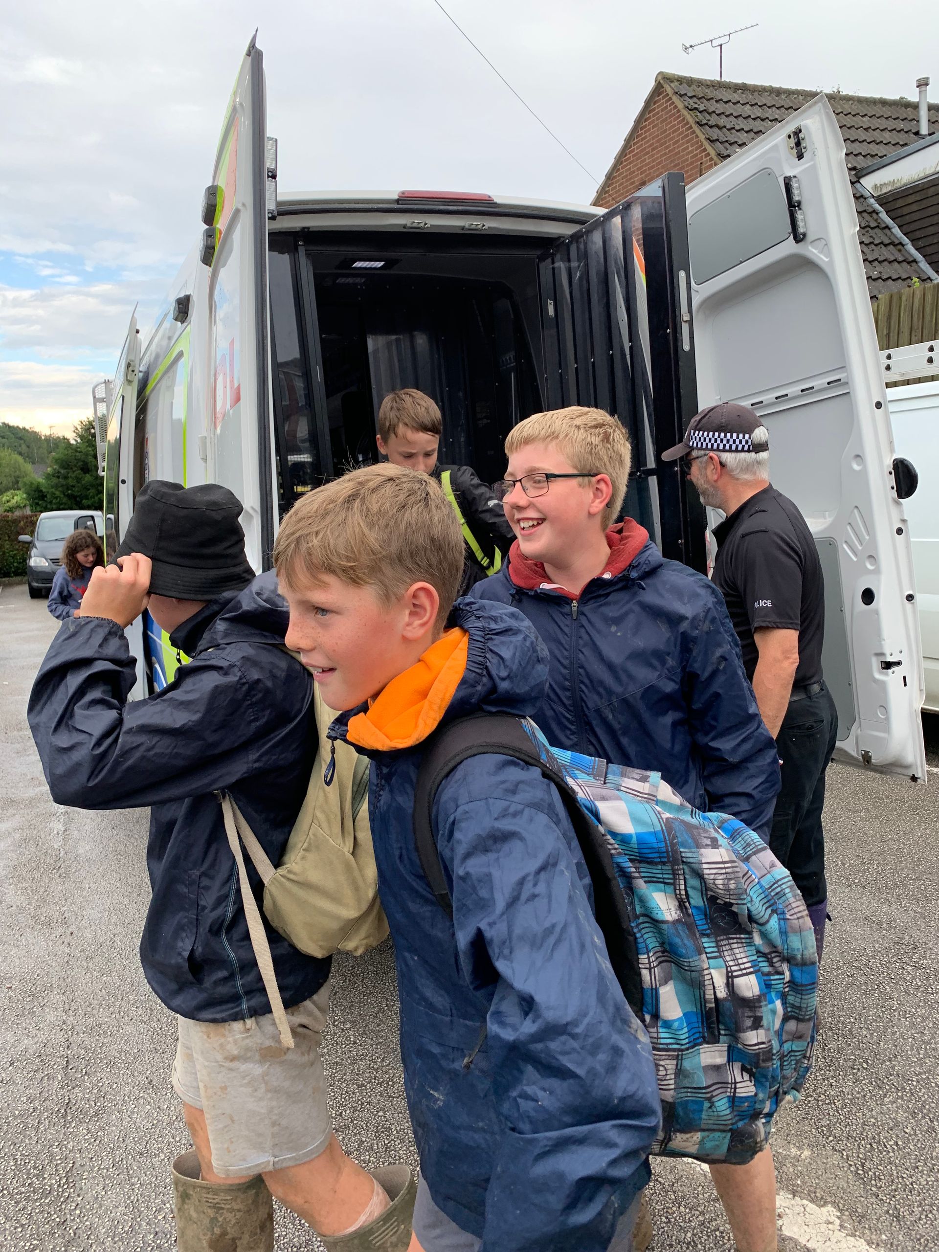 A group of young boys are standing in front of a van.