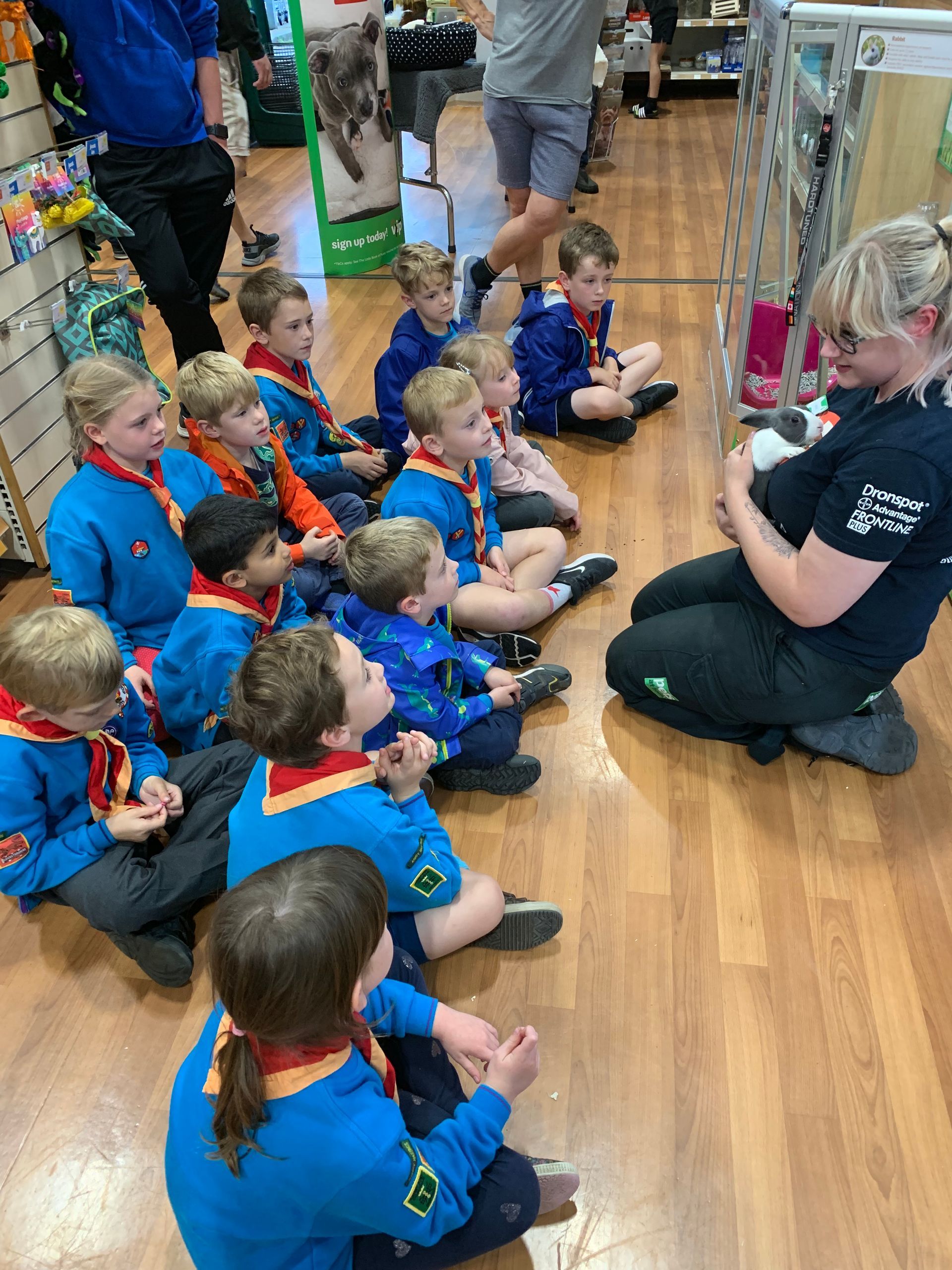 A group of children are sitting on the floor listening to a woman