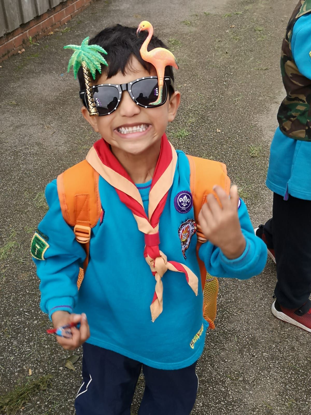 A young boy wearing sunglasses has a flamingo on his head