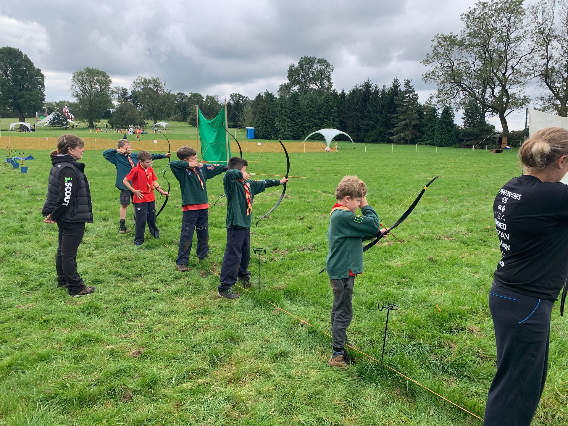 A group of children are practicing archery in a field.