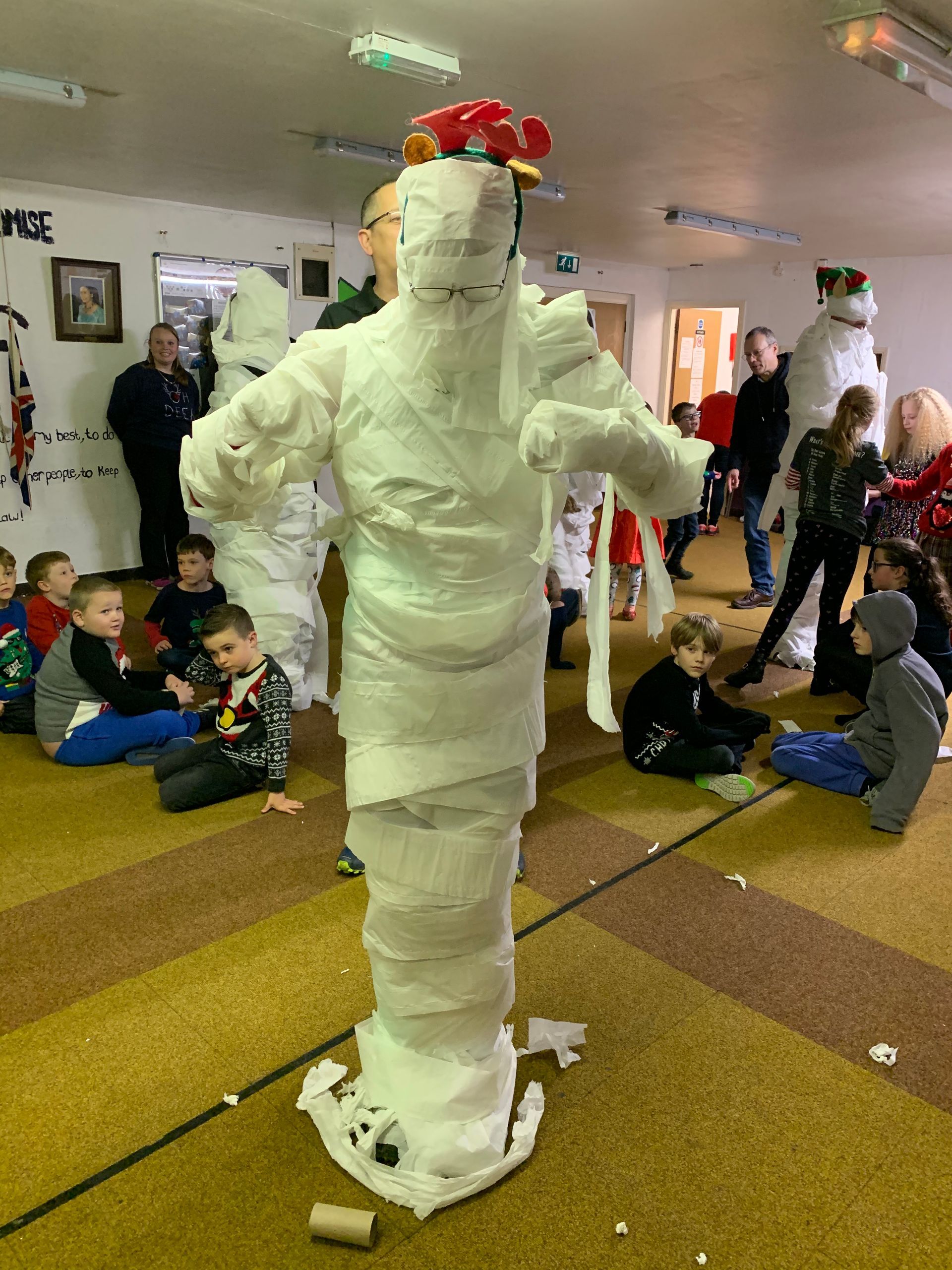 A group of children are playing with a mummy made out of toilet paper.